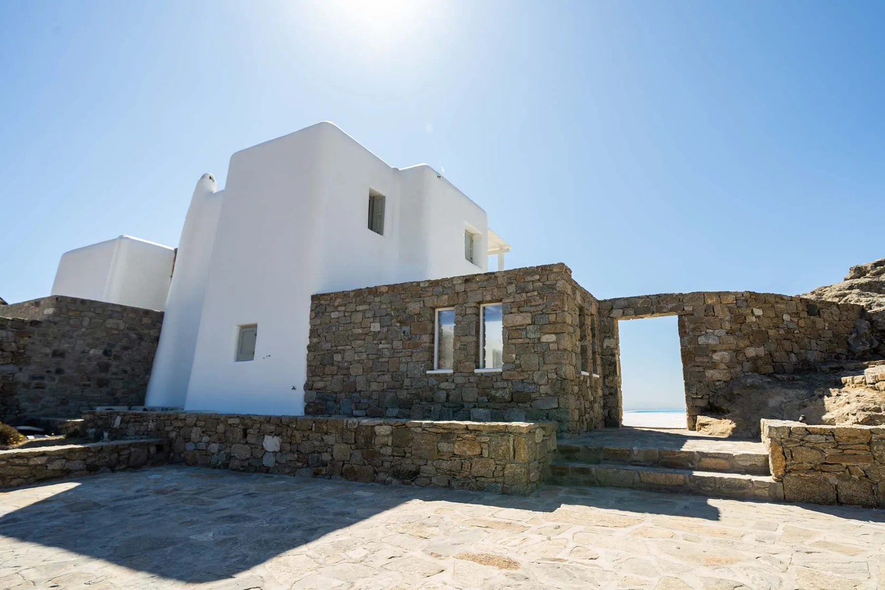 A white building stands beside stone walls and an open doorway.