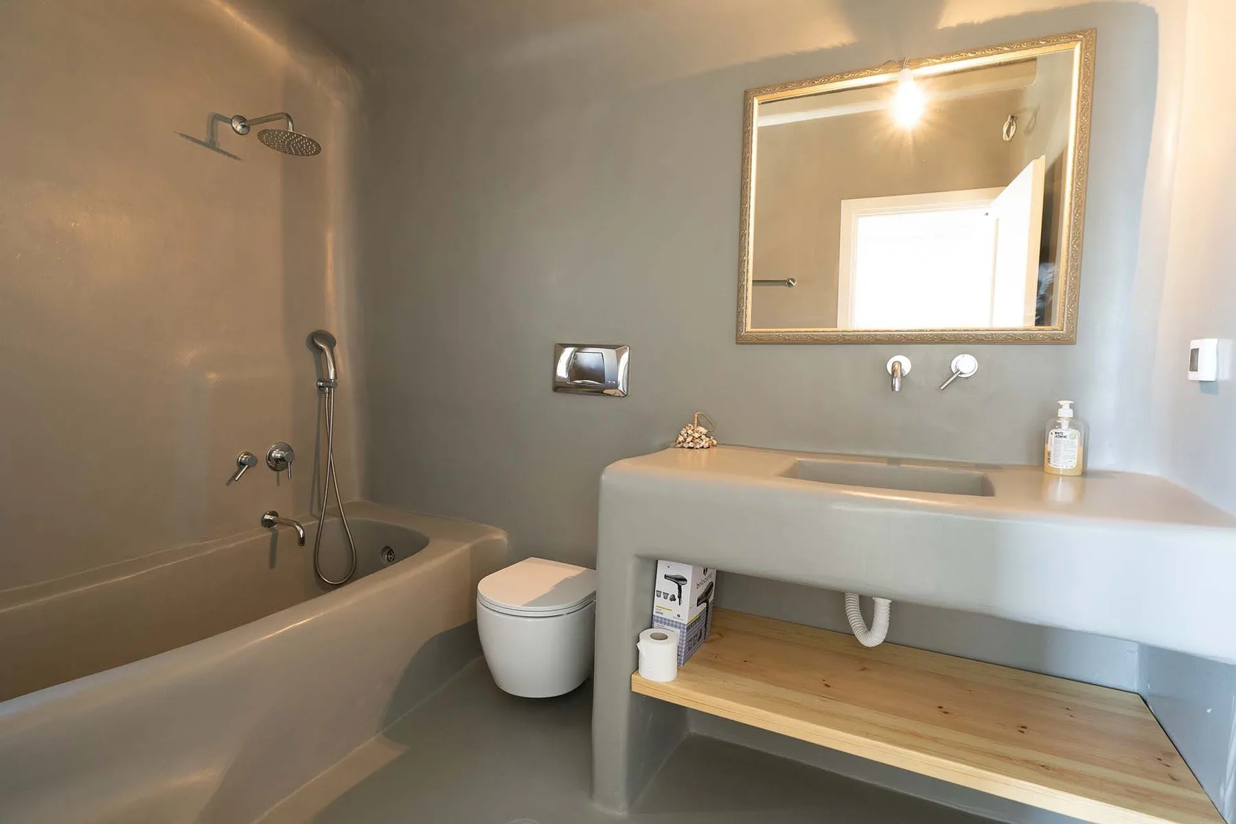 A bathroom with a bathtub, shower, and wide sink beneath a mirror.
