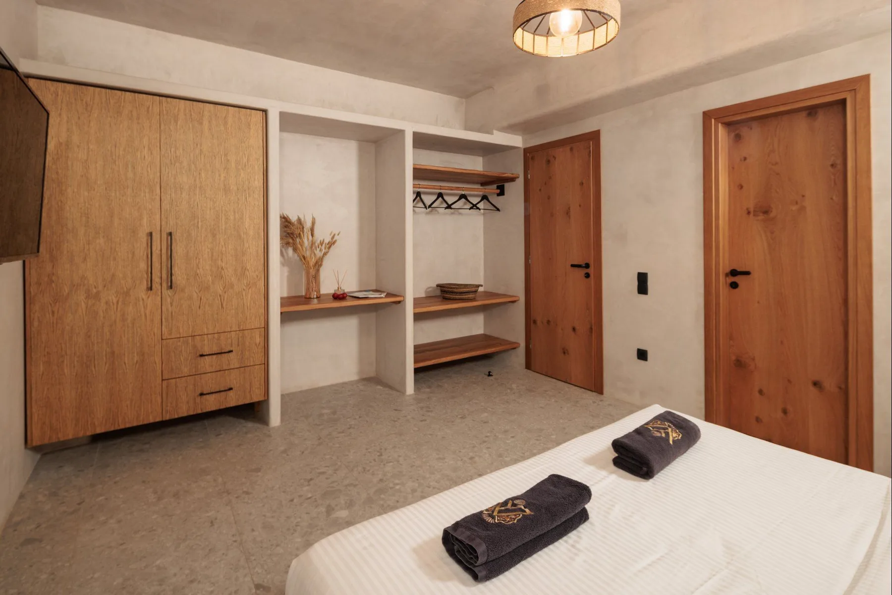 A bedroom with a bed in the foreground and wooden doors along the wall.