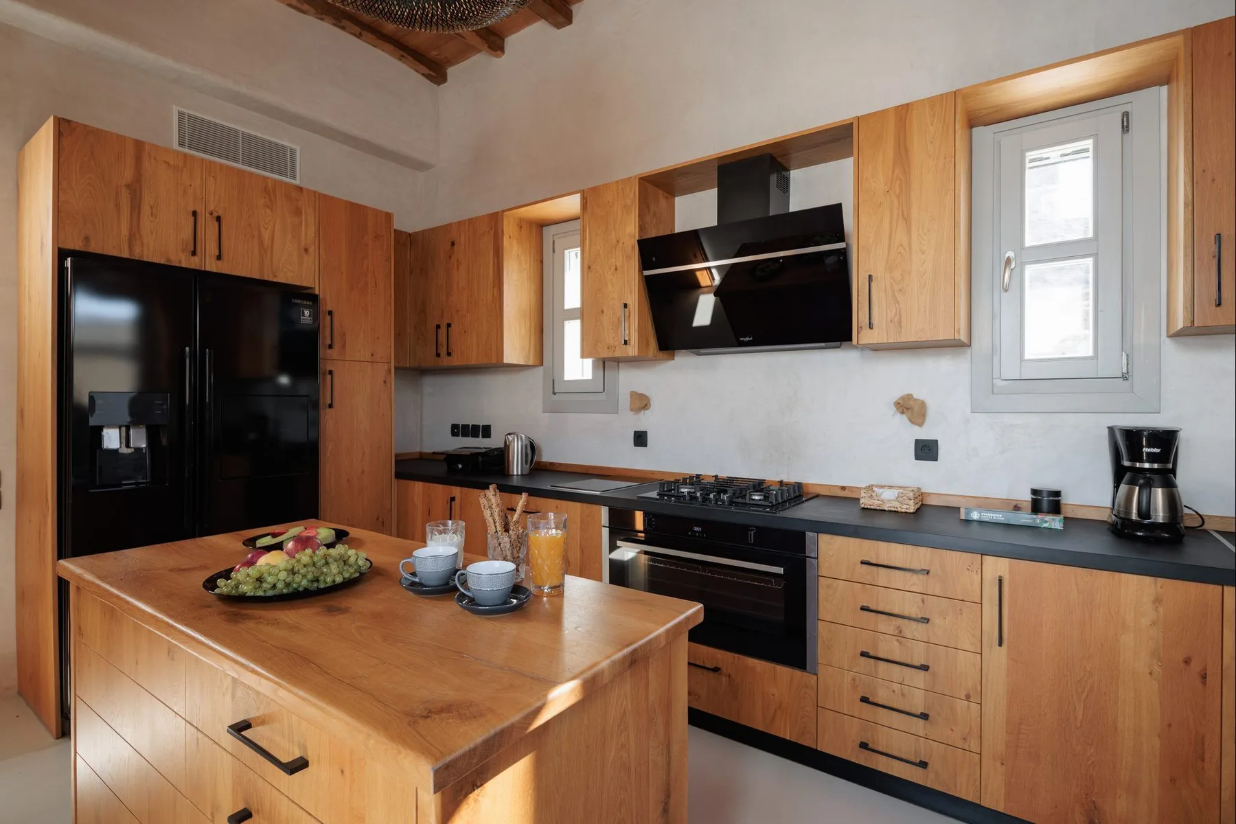 A kitchen with wooden cabinets, a central island, and black appliances.