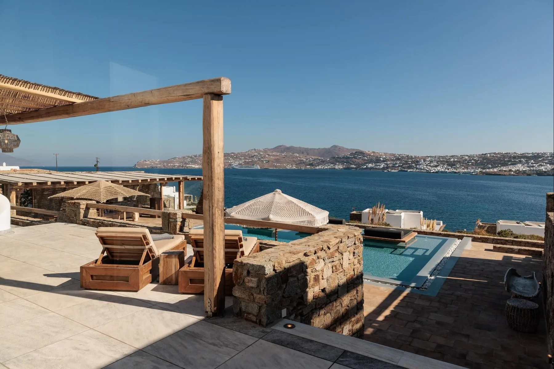 A seaside terrace with lounge seating and a swimming pool overlooking the water.