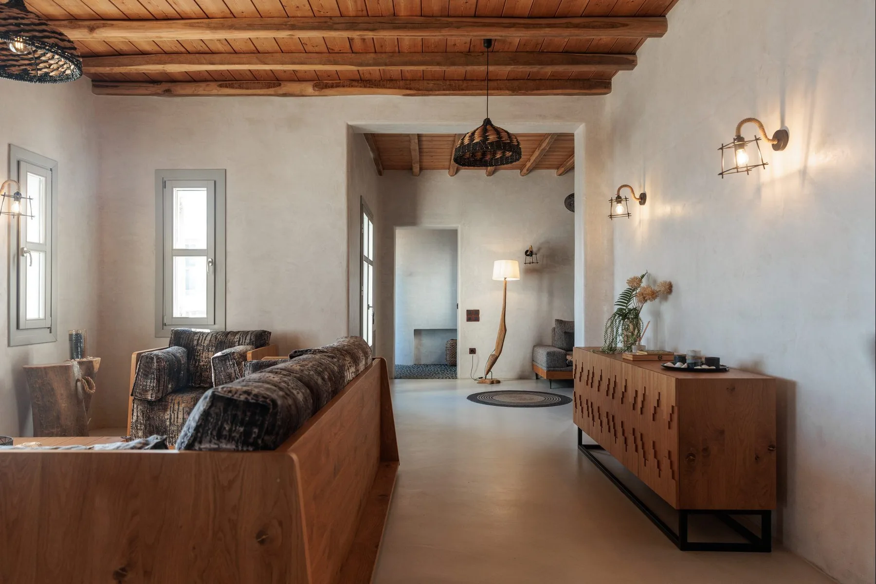 A living room with seating, a wooden cabinet, and exposed ceiling beams.