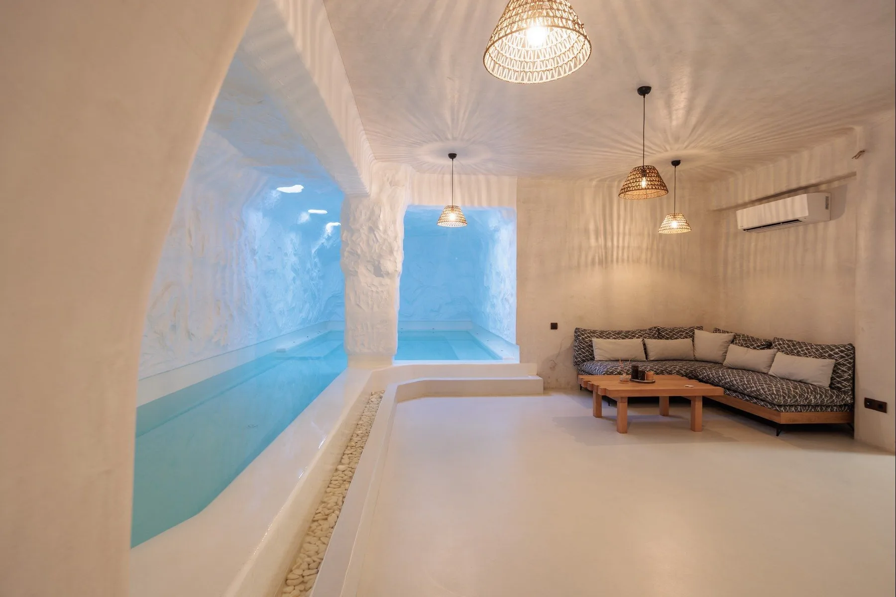 A white indoor pool beside a built-in seating area with patterned cushions.