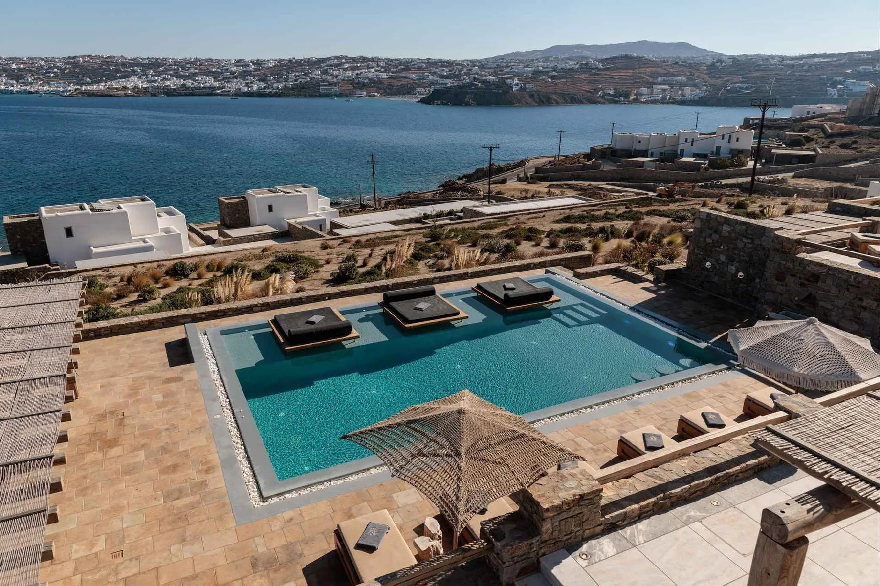 A pool terrace overlooks the bay and distant hillside buildings.