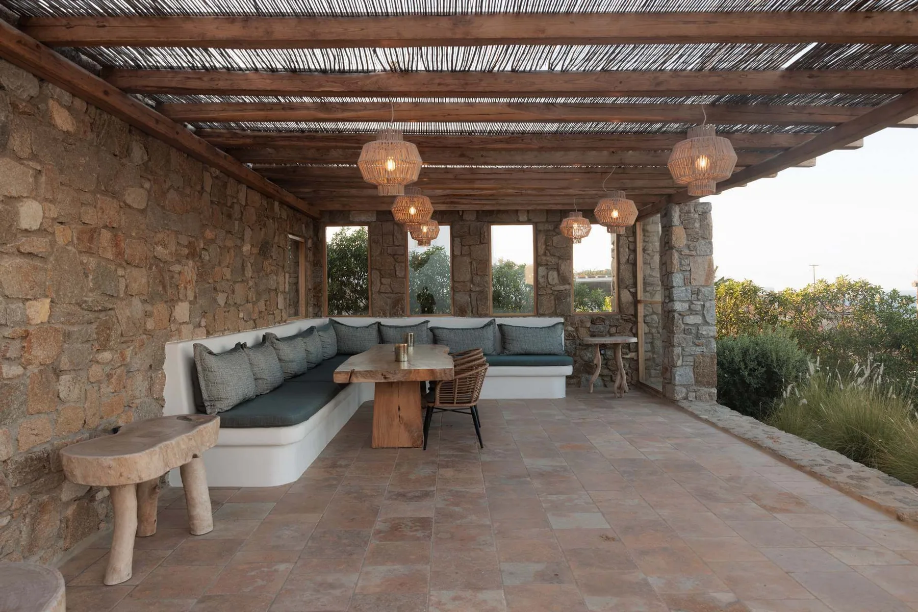 A covered outdoor seating area with cushioned benches and hanging lights.