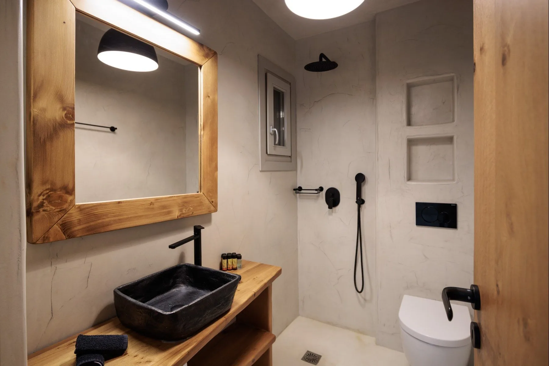 A bathroom with a sink, wall mirror, shower fixtures, and toilet.