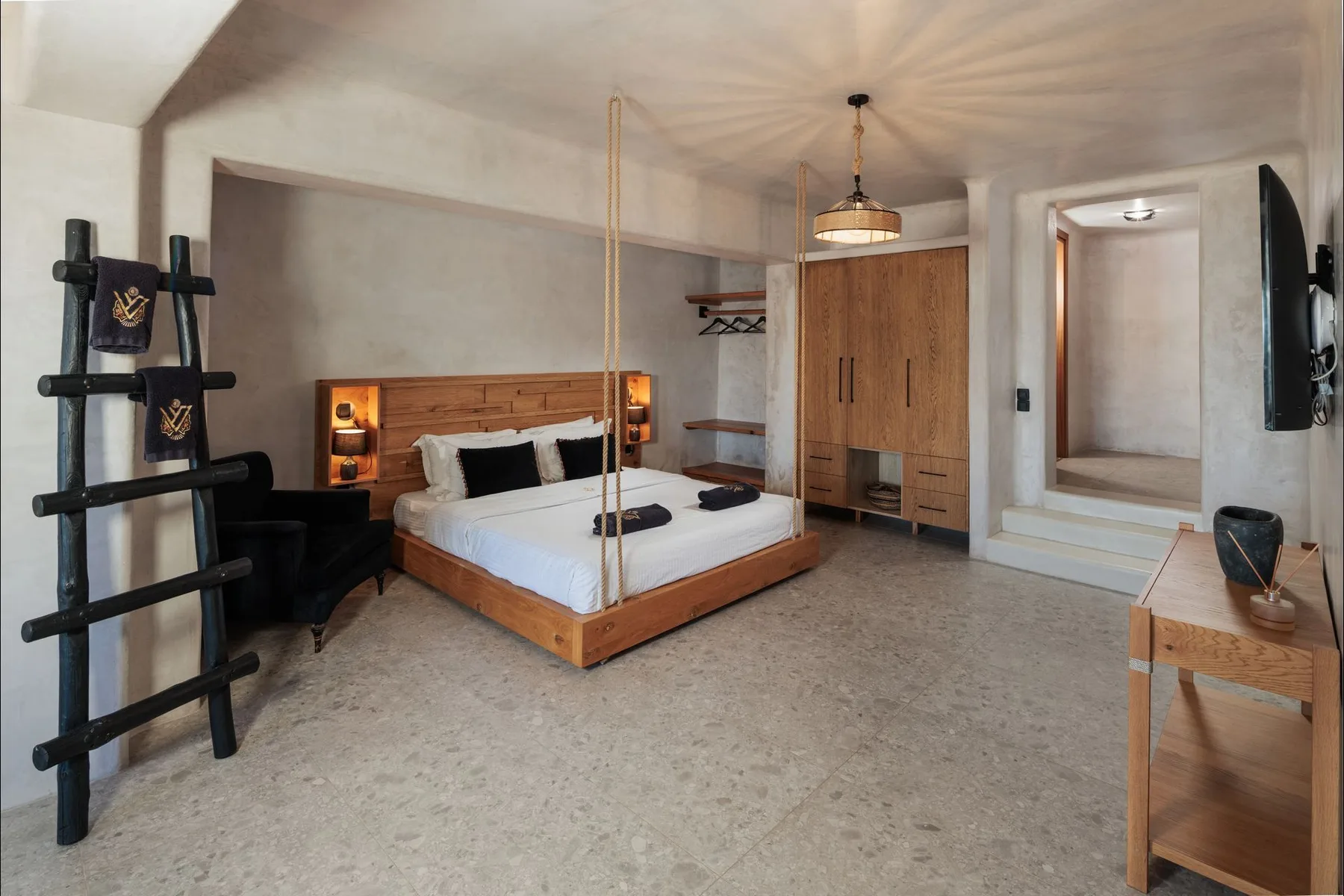 A bedroom with a wooden bed, built-in wardrobe, and a wall-mounted television.