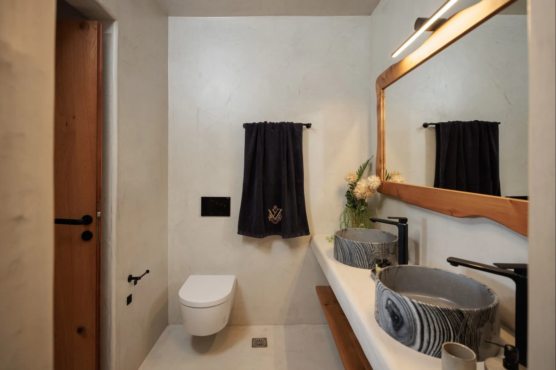 A bathroom with a toilet, a long sink, and a large mirror.