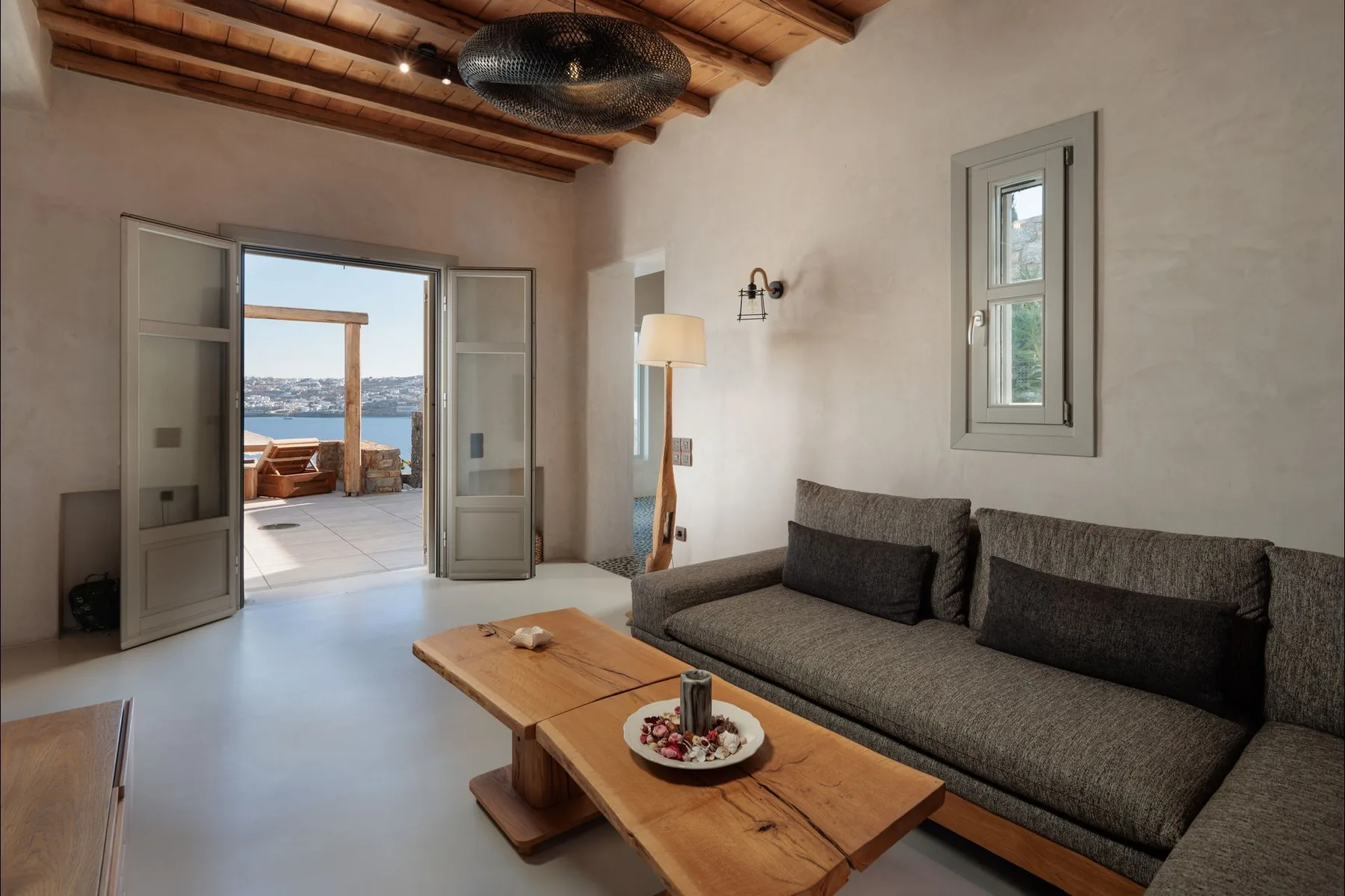 A living room with a dark sofa and wooden coffee table beside open doors to a terrace.