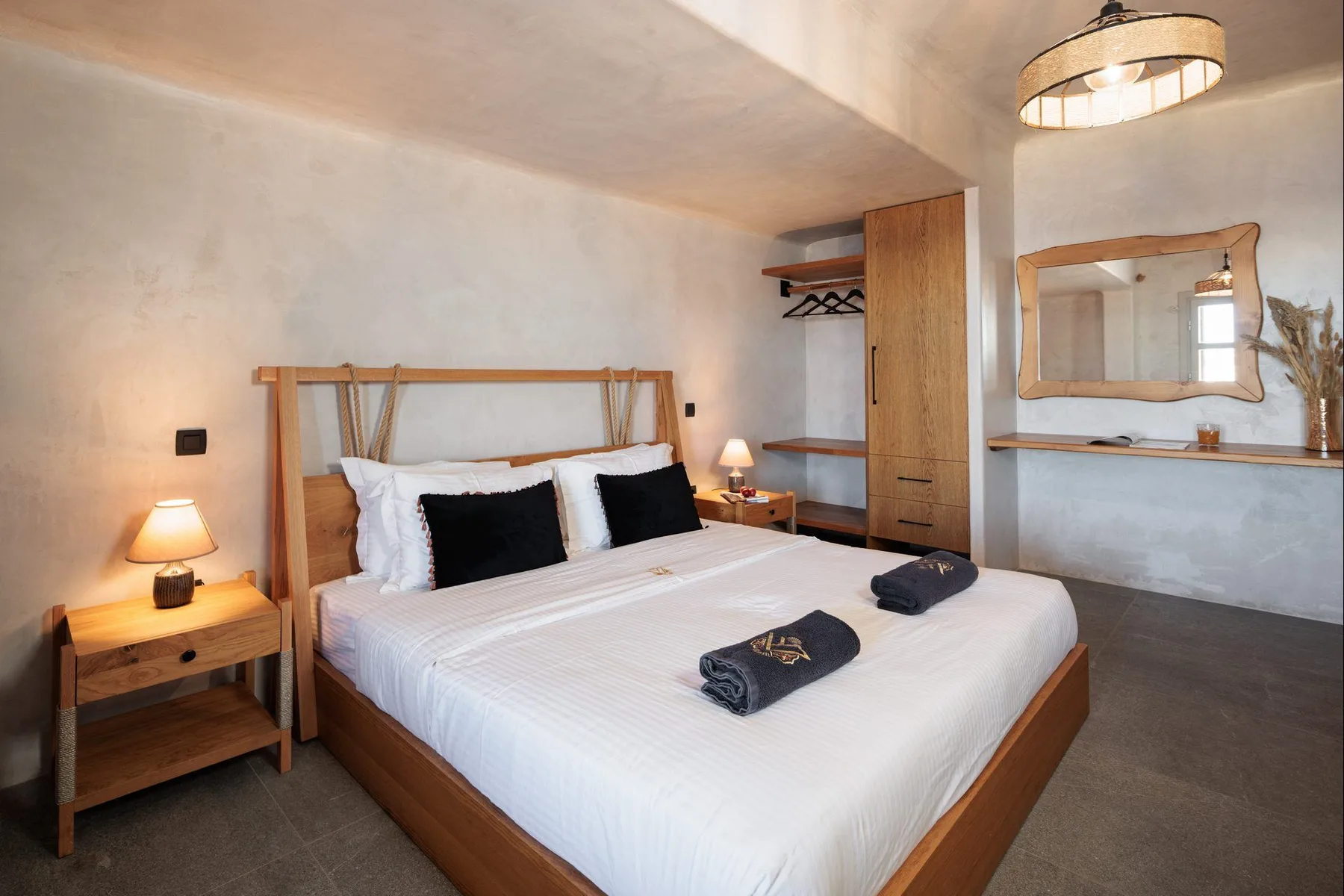 A bedroom with a made bed, bedside tables, and a wall mirror.