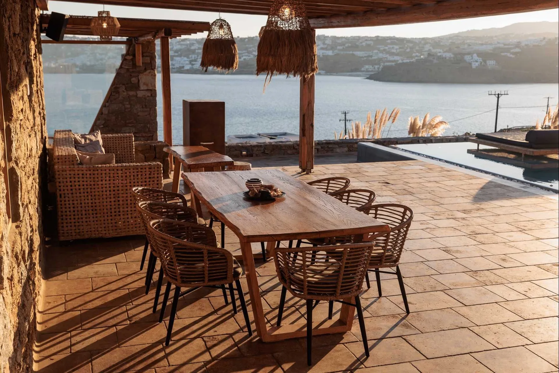 A covered outdoor dining area with a wooden table and a view of the water.