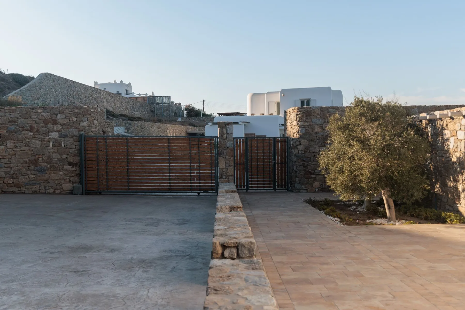 A paved outdoor entrance with a wooden gate set in stone walls.
