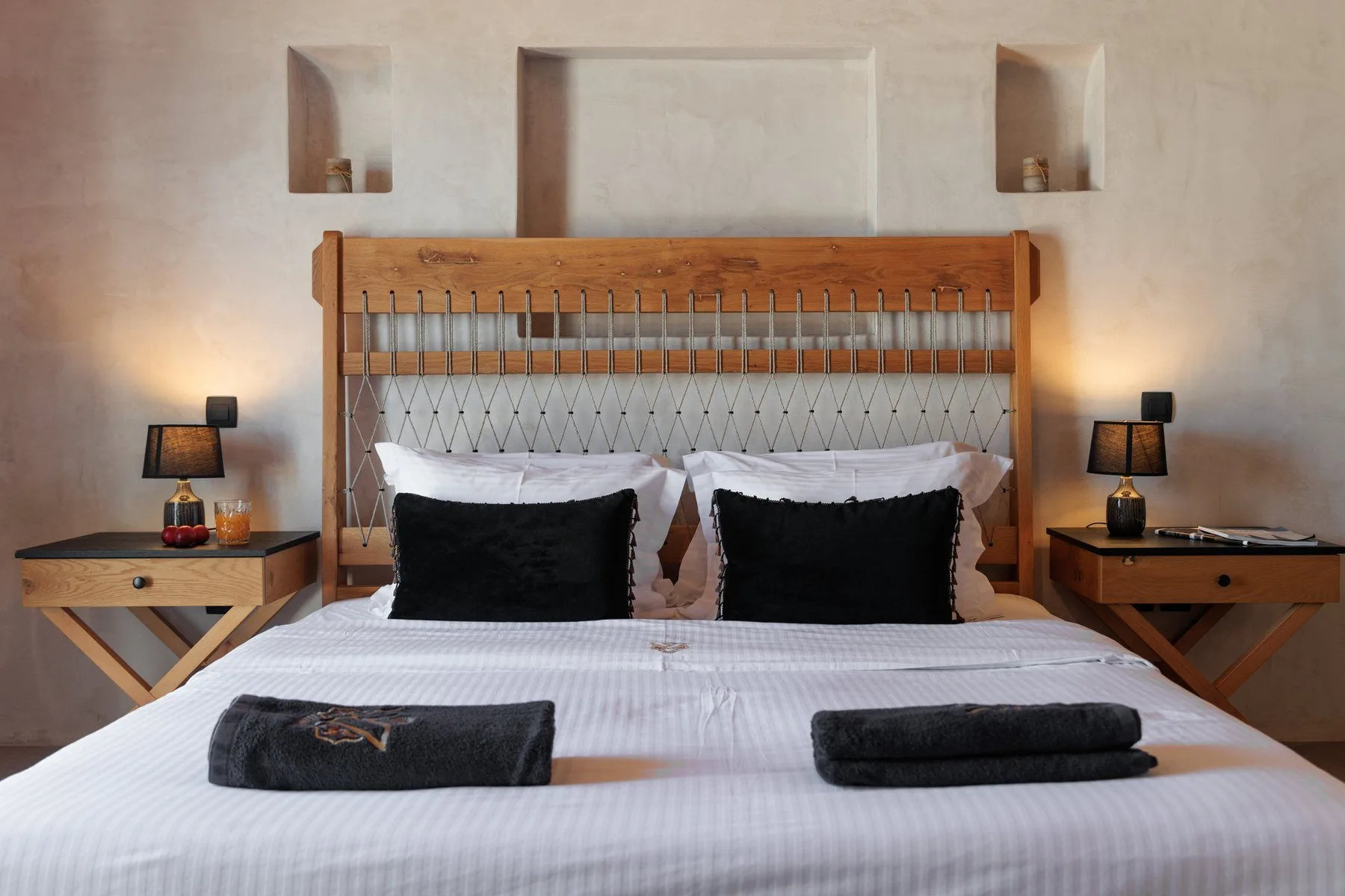 A bedroom with a wooden bed, white bedding, and matching bedside tables.
