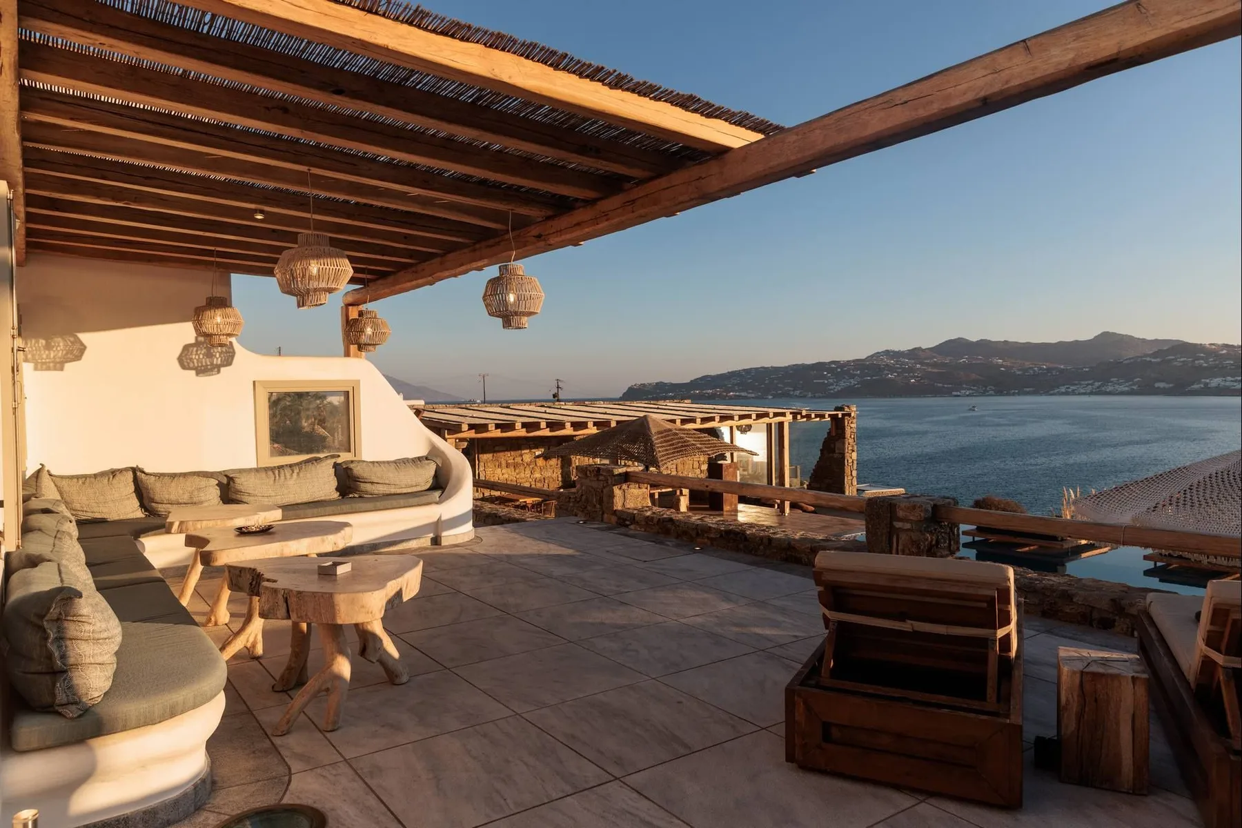 A seaside terrace with cushioned seating and a view across the water.
