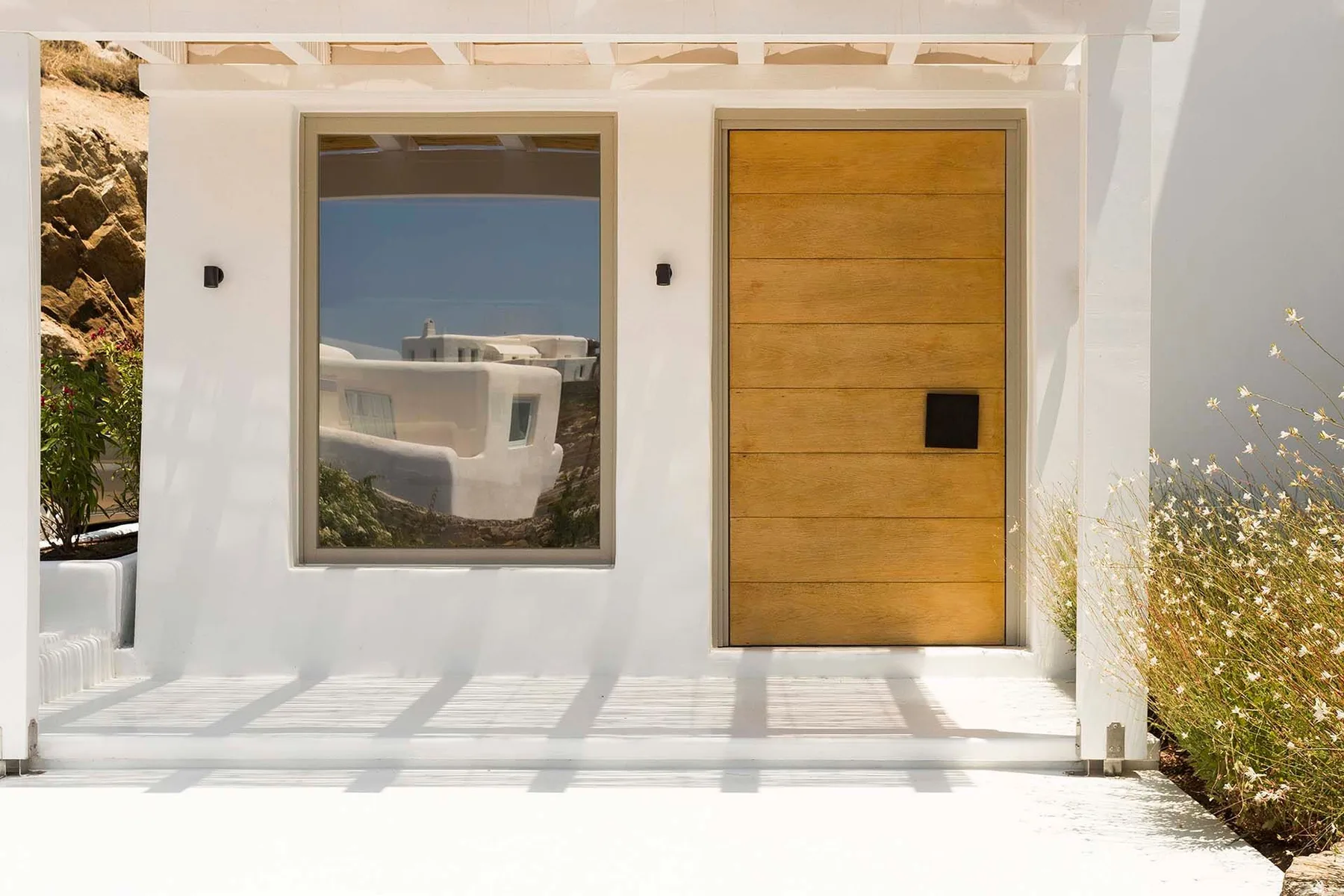 A white building entrance with a wooden door and a large window.