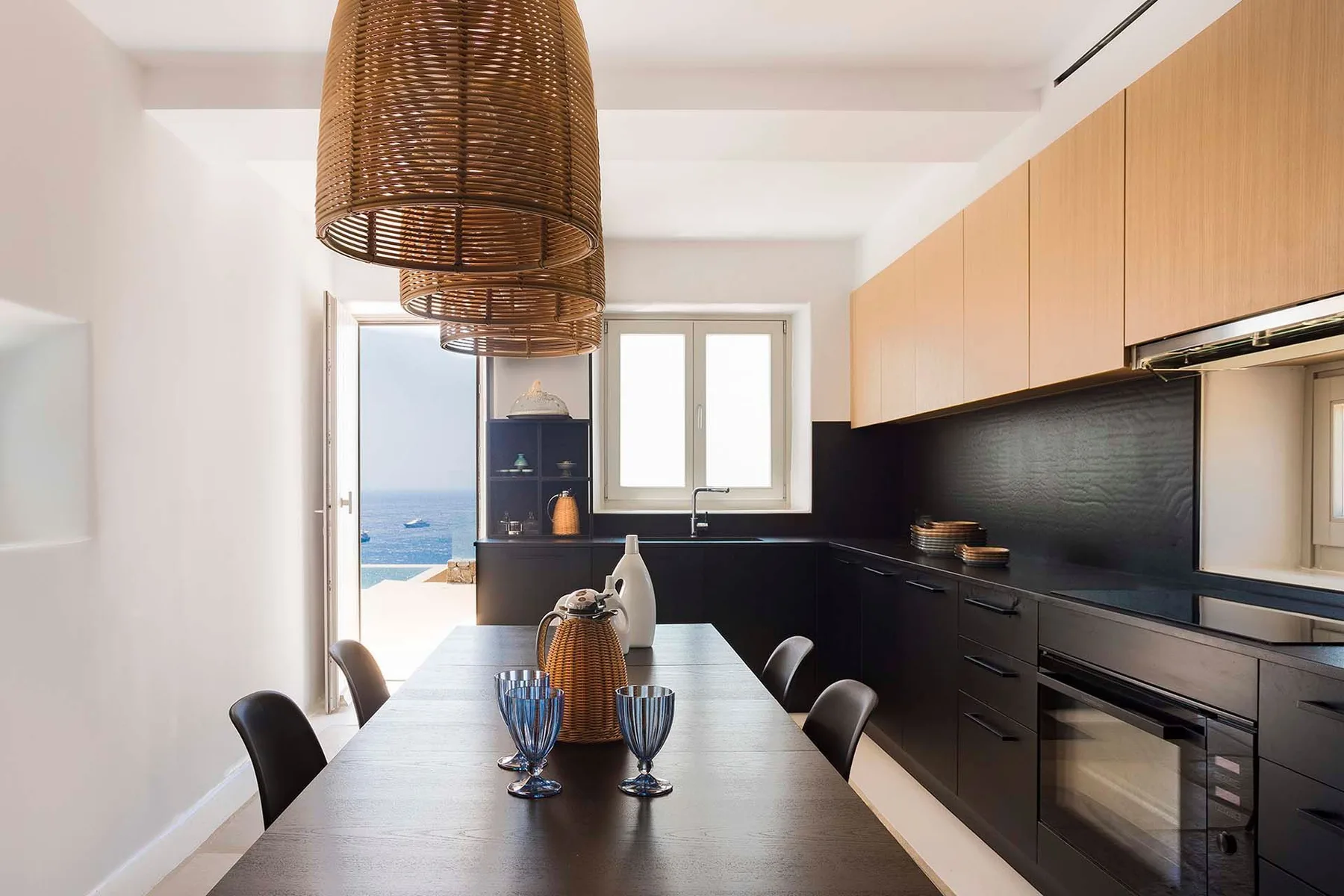 A modern kitchen and dining area with a table set beside a sea view.
