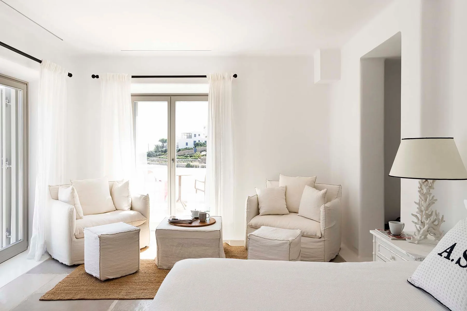 A bright living room with light-colored seating beside large windows.