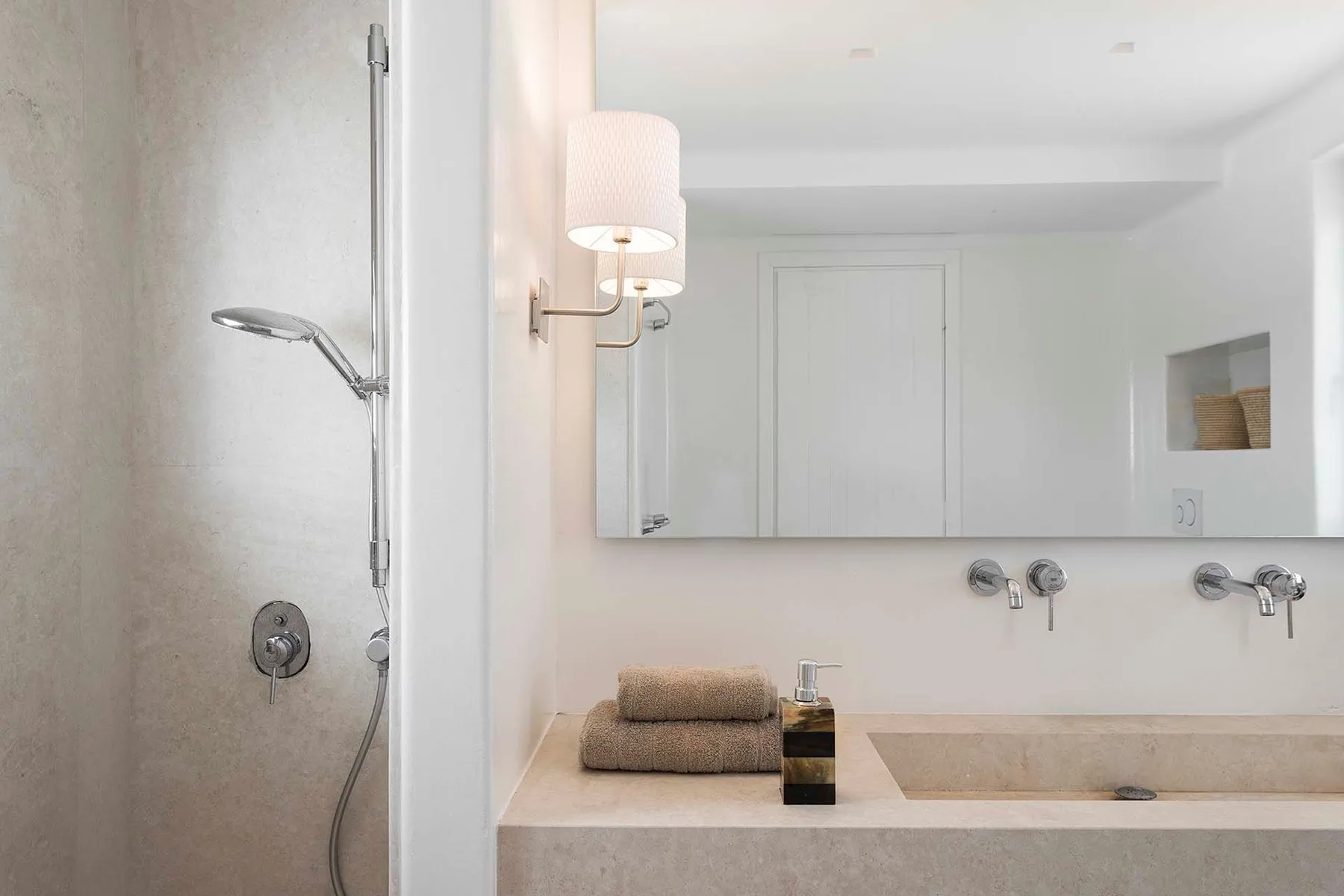 A bright bathroom with a shower and a wide sink counter beneath a mirror.