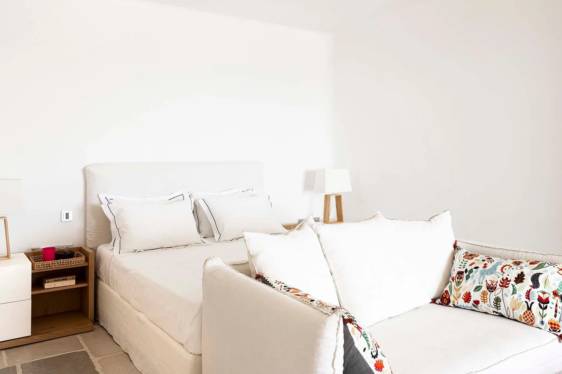 A bright bedroom with a bed and a white seating area.