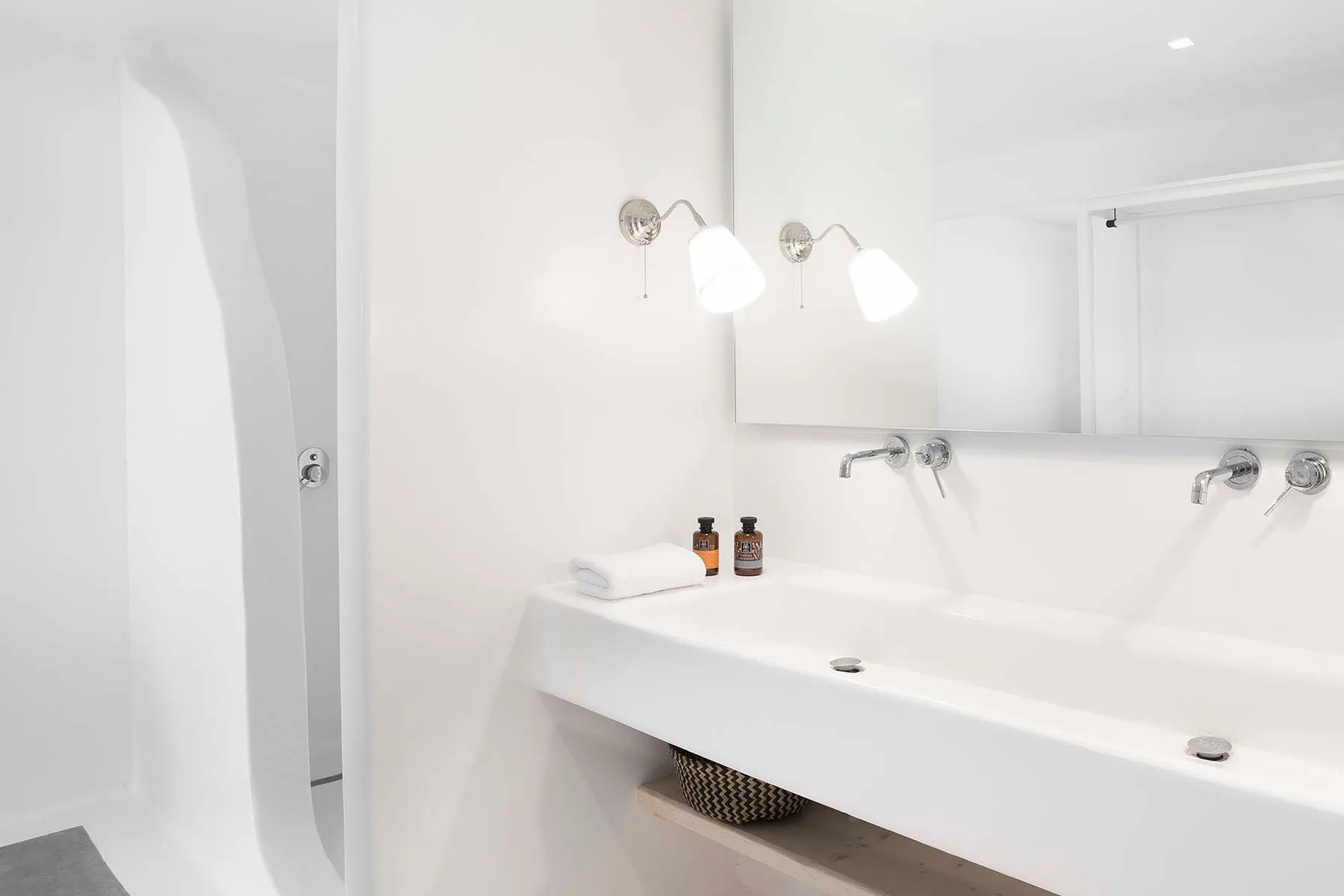 A bright bathroom with a long white sink beneath a wall mirror.