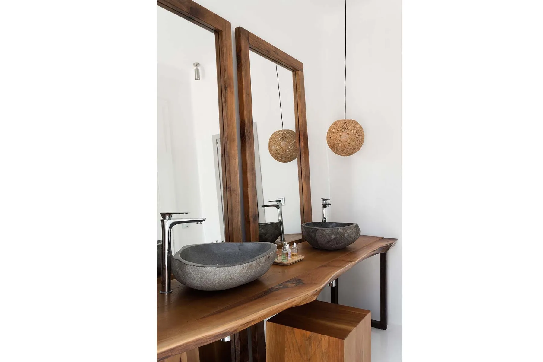 Bathroom vanity with two vessel sinks, wooden countertop, and pendant lights.
