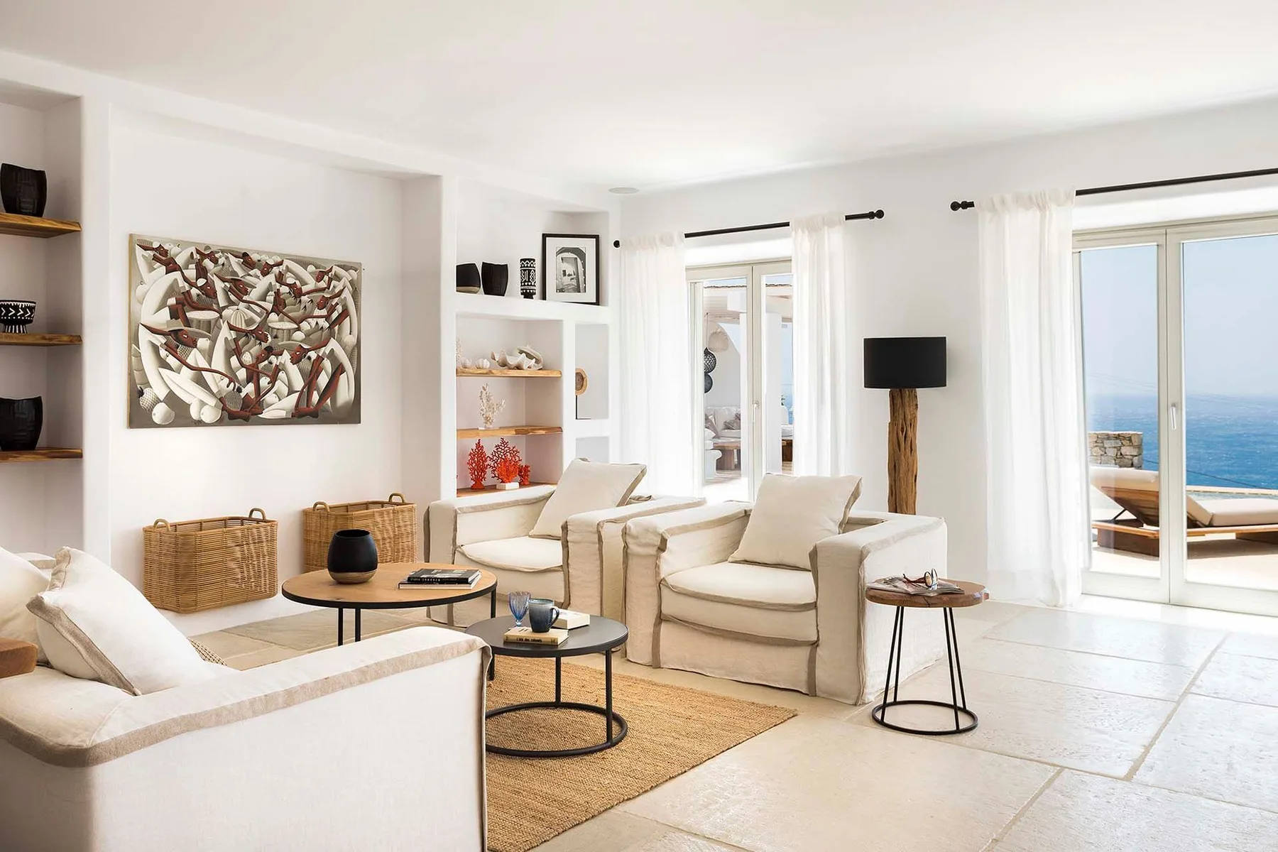A bright living room with light seating and large windows opening onto a patio.