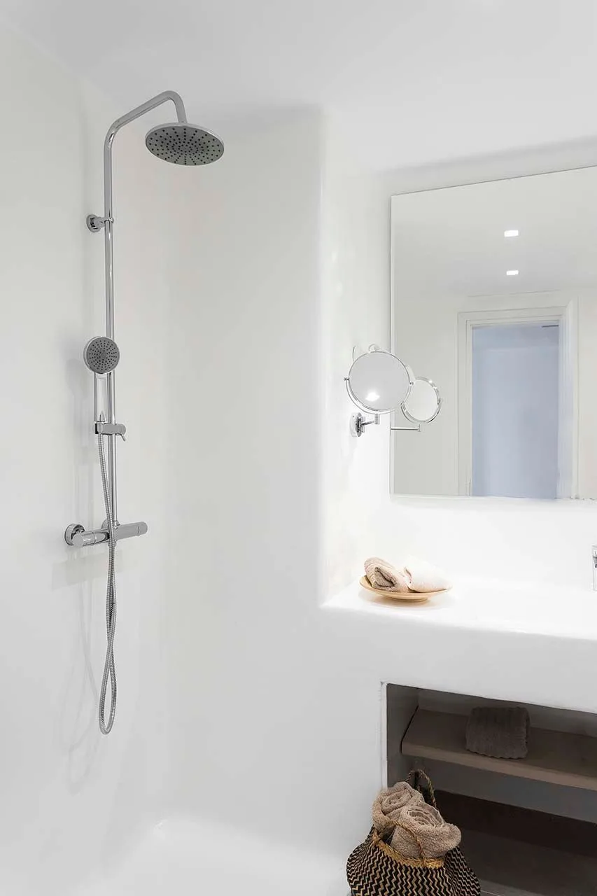 A bright bathroom with a wall-mounted shower and a large mirror.