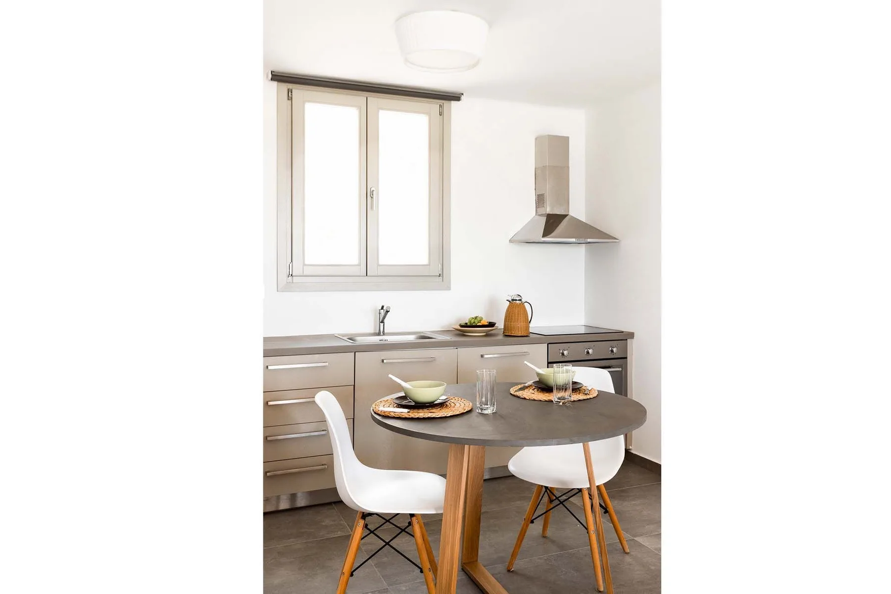 A bright kitchen with a round dining table set for a meal.