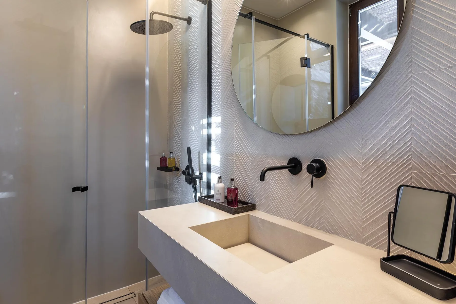 Un baño moderno con un amplio lavabo, grifo de pared y ducha de vidrio.