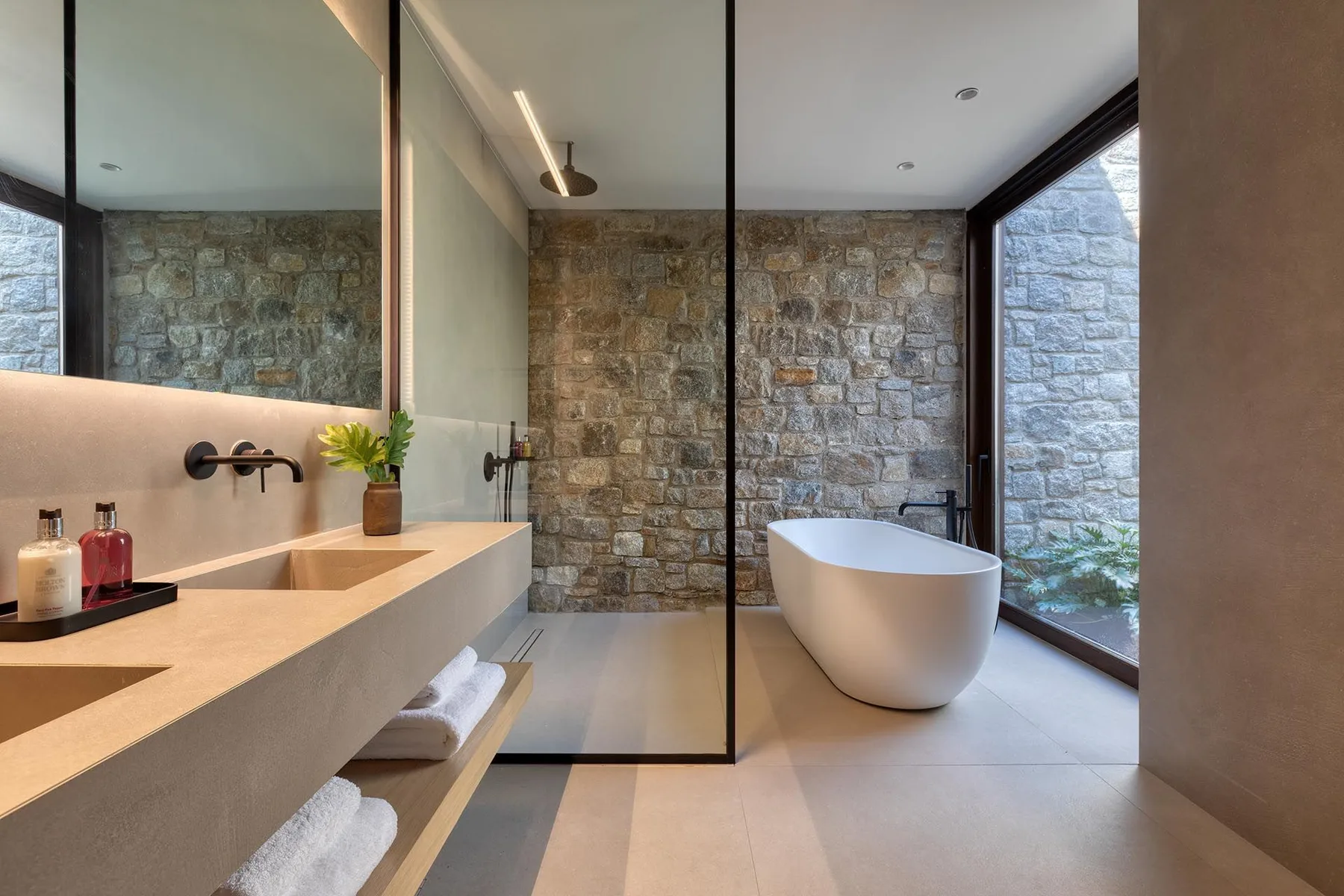 Un baño con una bañera exenta junto a una ventana grande.