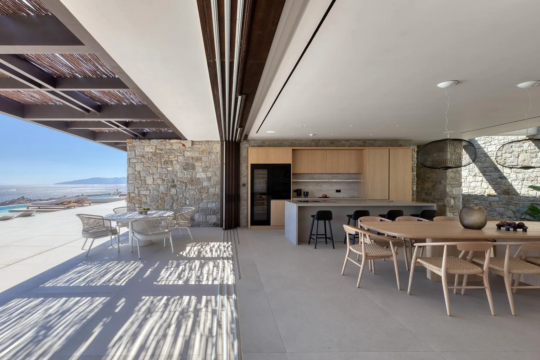 Una zona de comedor exterior cubierta se abre a una terraza con vistas al mar.