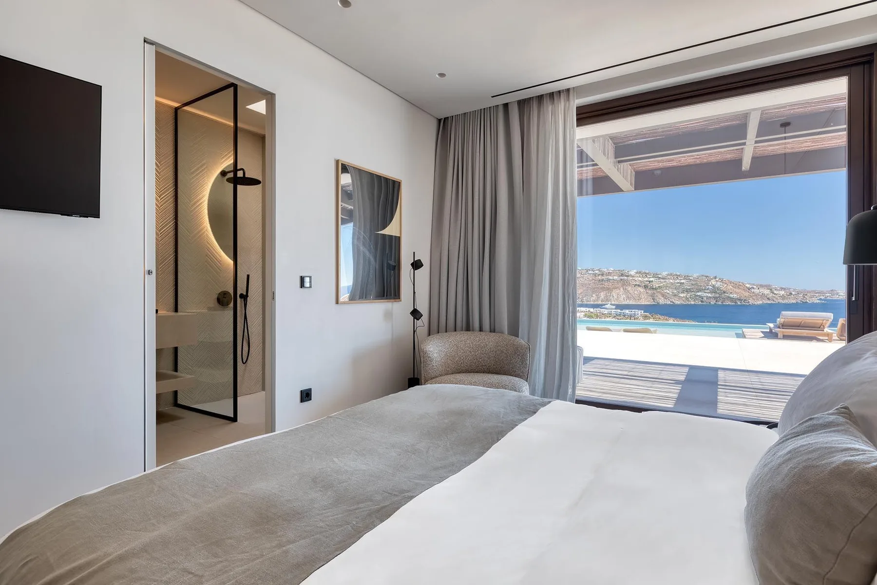 Un dormitorio con una cama, una entrada abierta al baño y vistas al mar.