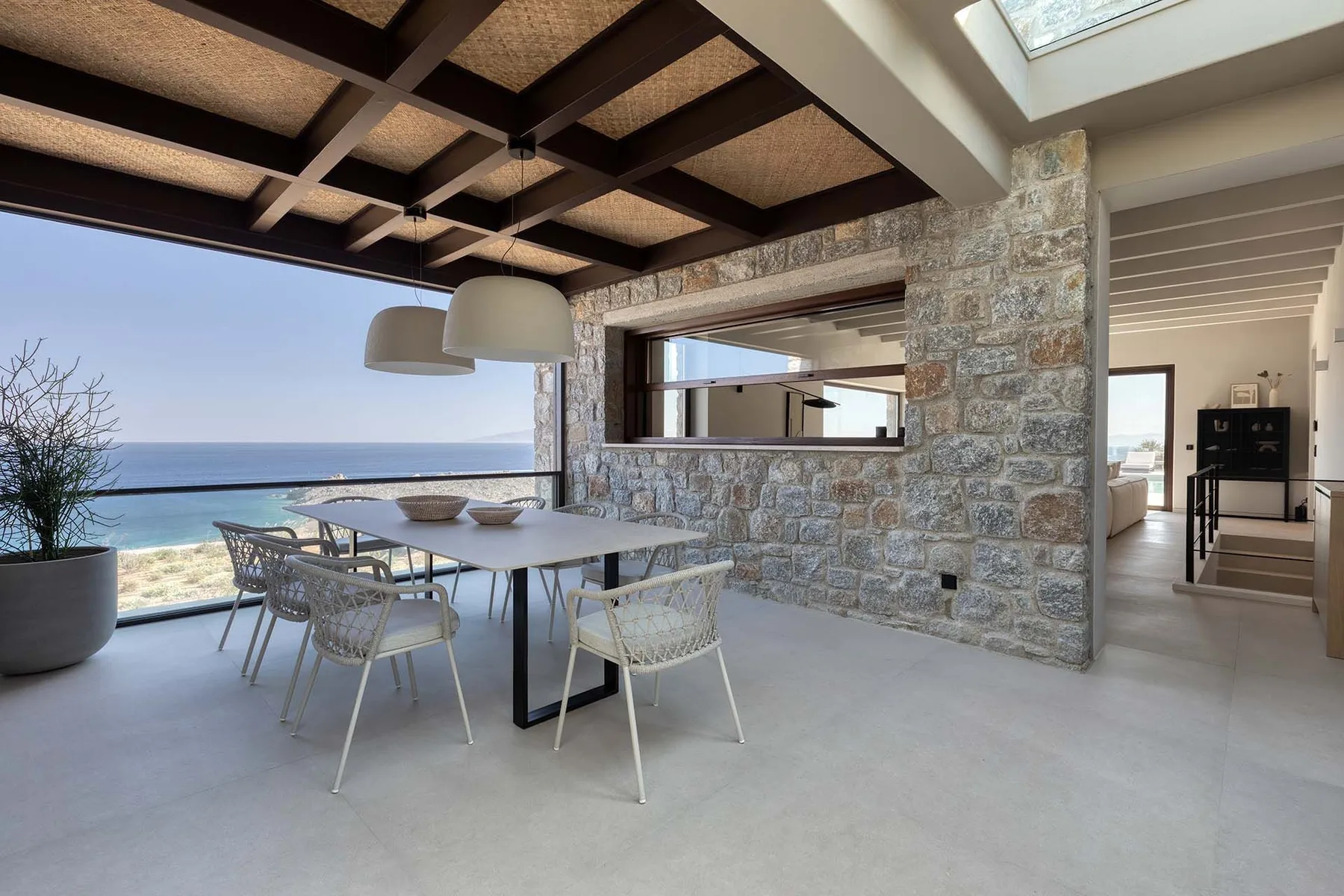 Un comedor abierto con una mesa junto a una amplia vista al mar.