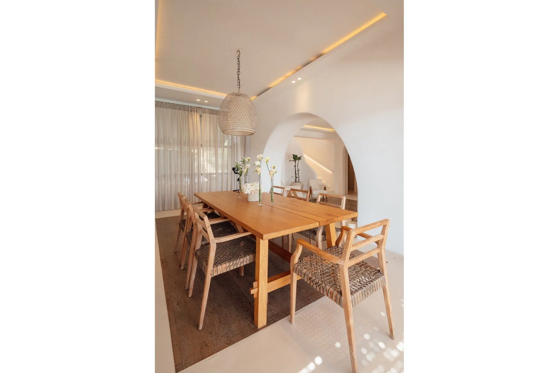 A dining area with a long wooden table and woven chairs.