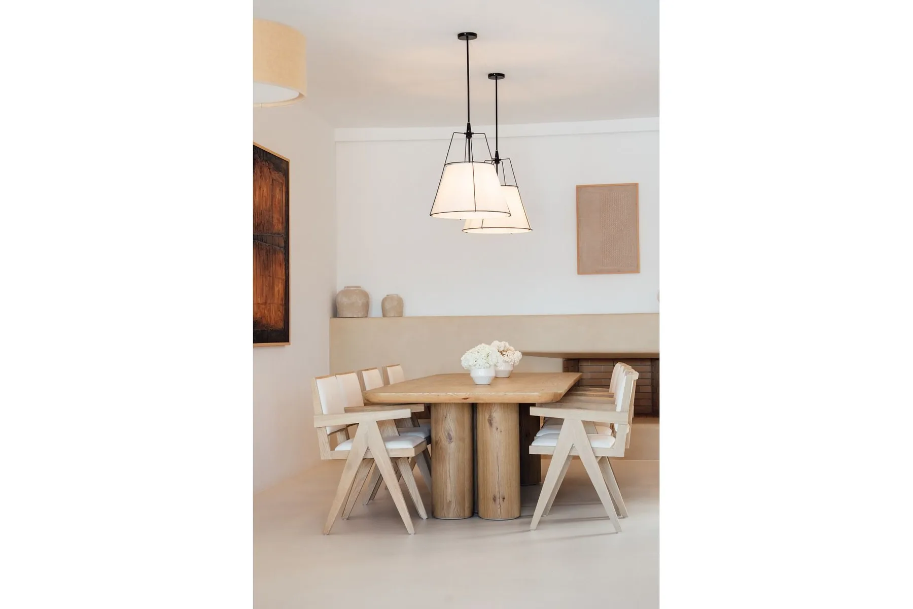 A dining area with a wooden table, seating, and pendant lights.