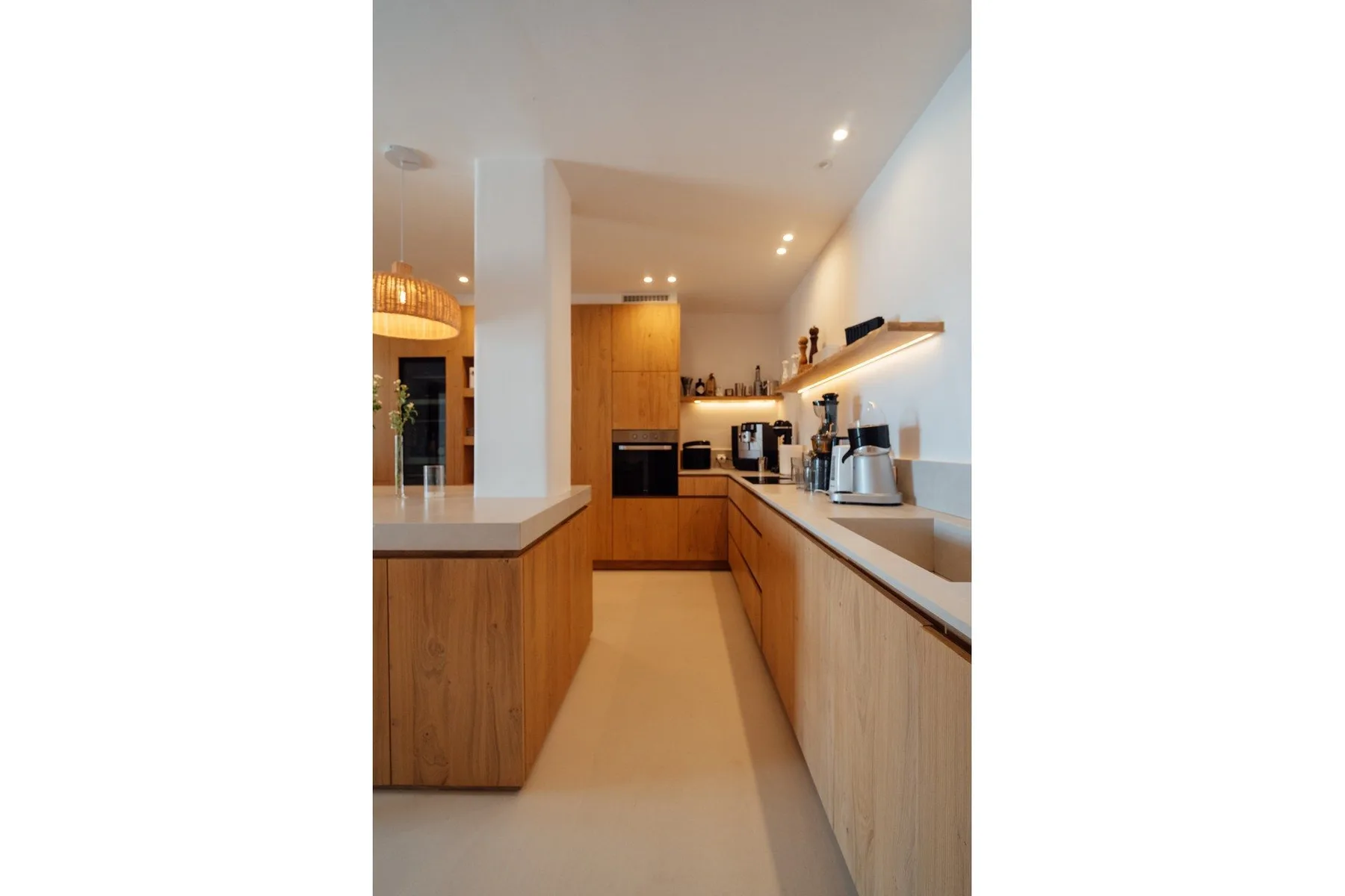 A modern kitchen with wood cabinetry and a long countertop.