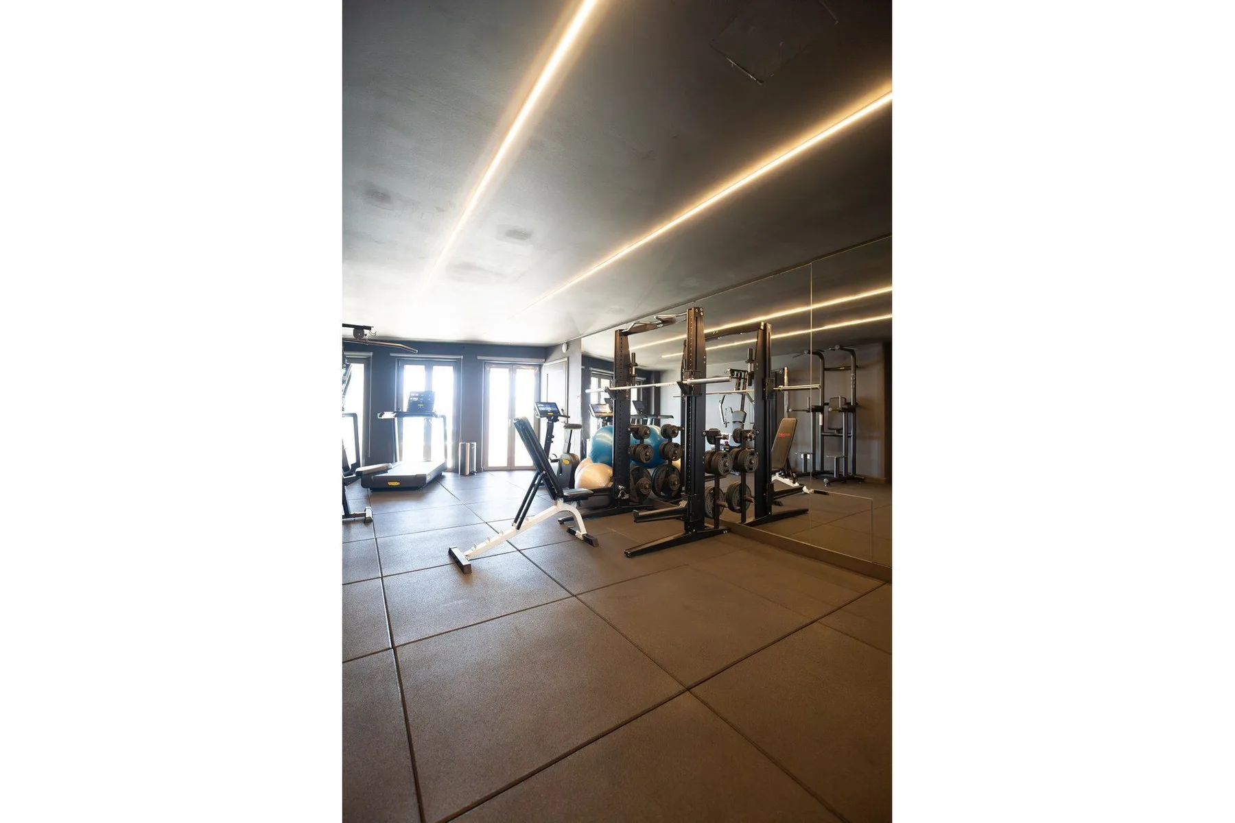 A fitness room with exercise equipment and mirrored walls.