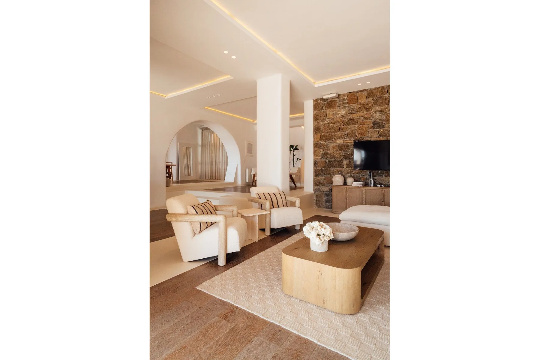 A bright living room features seating around a low coffee table and a stone accent wall.