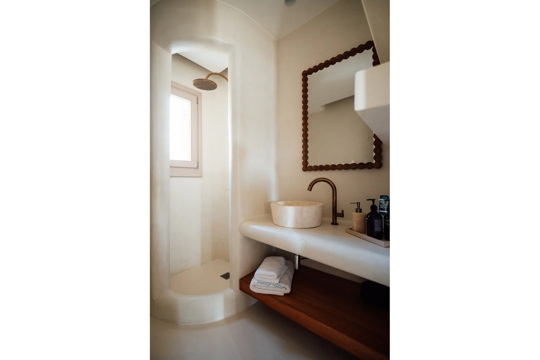 A bathroom with a walk-in shower and a sink beneath a framed mirror.