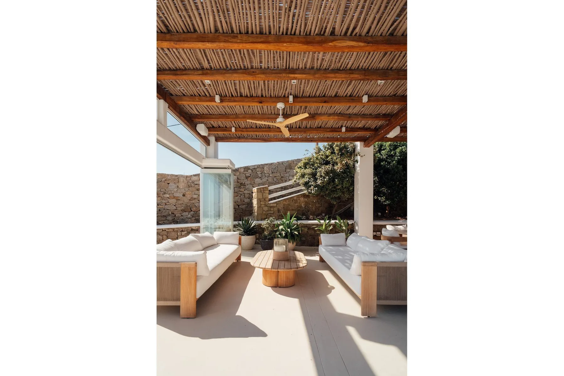 A covered outdoor lounge with cushioned seating and a low wooden table.