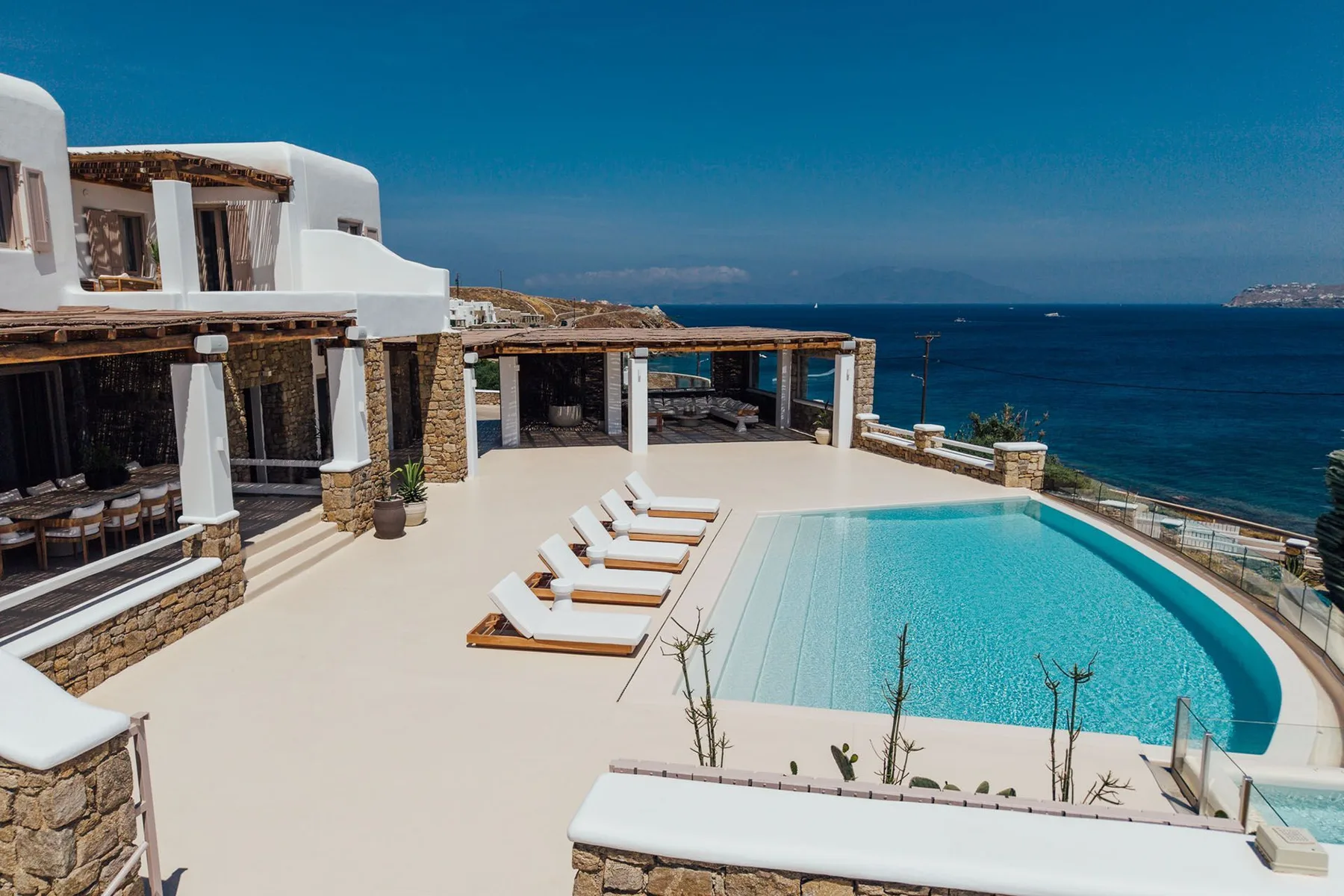 A seaside terrace with a curved swimming pool and lounge seating.
