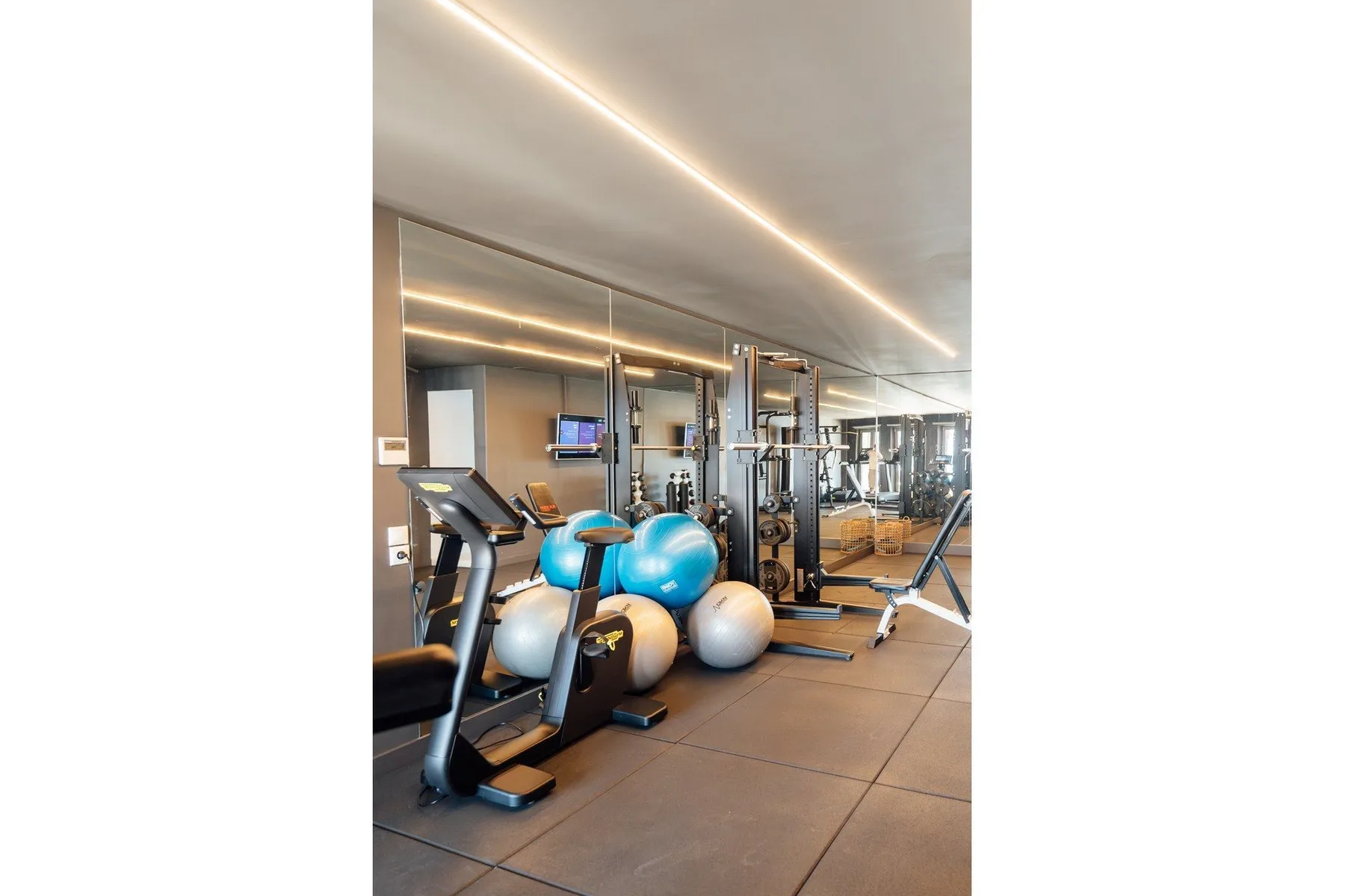A gym with exercise machines, weights, and bright blue exercise balls.