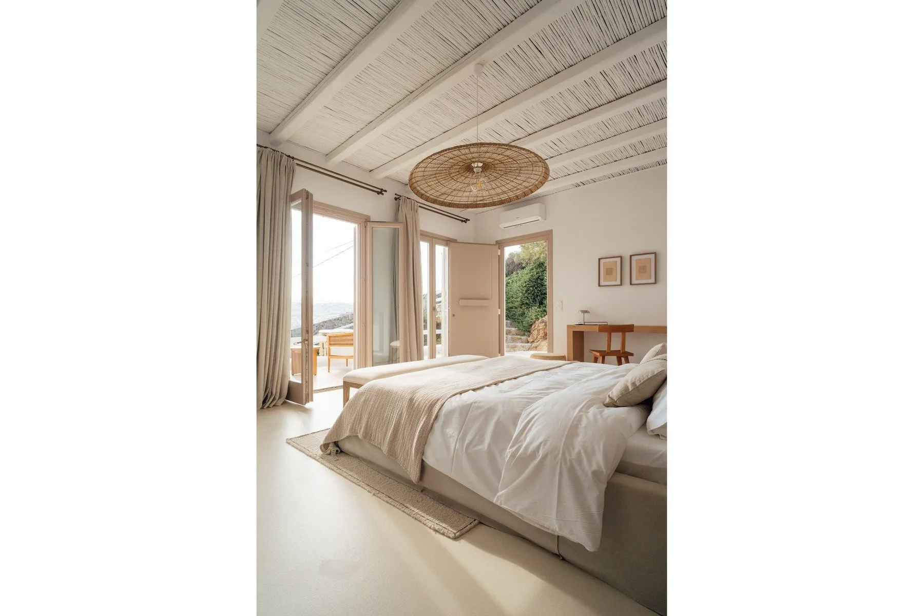 A bright bedroom with a bed and tall windows opening onto a balcony.
