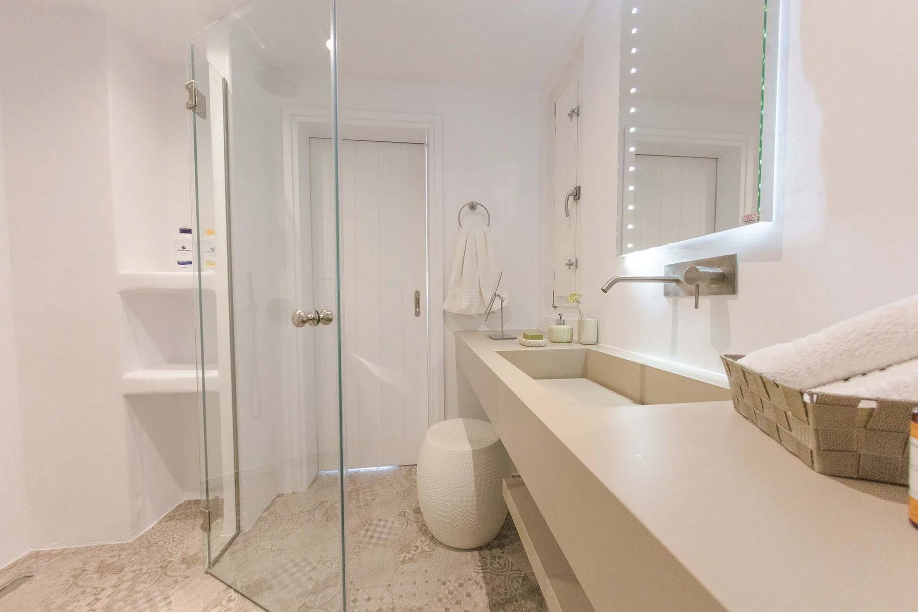 A bright bathroom with a glass shower and a long sink counter.