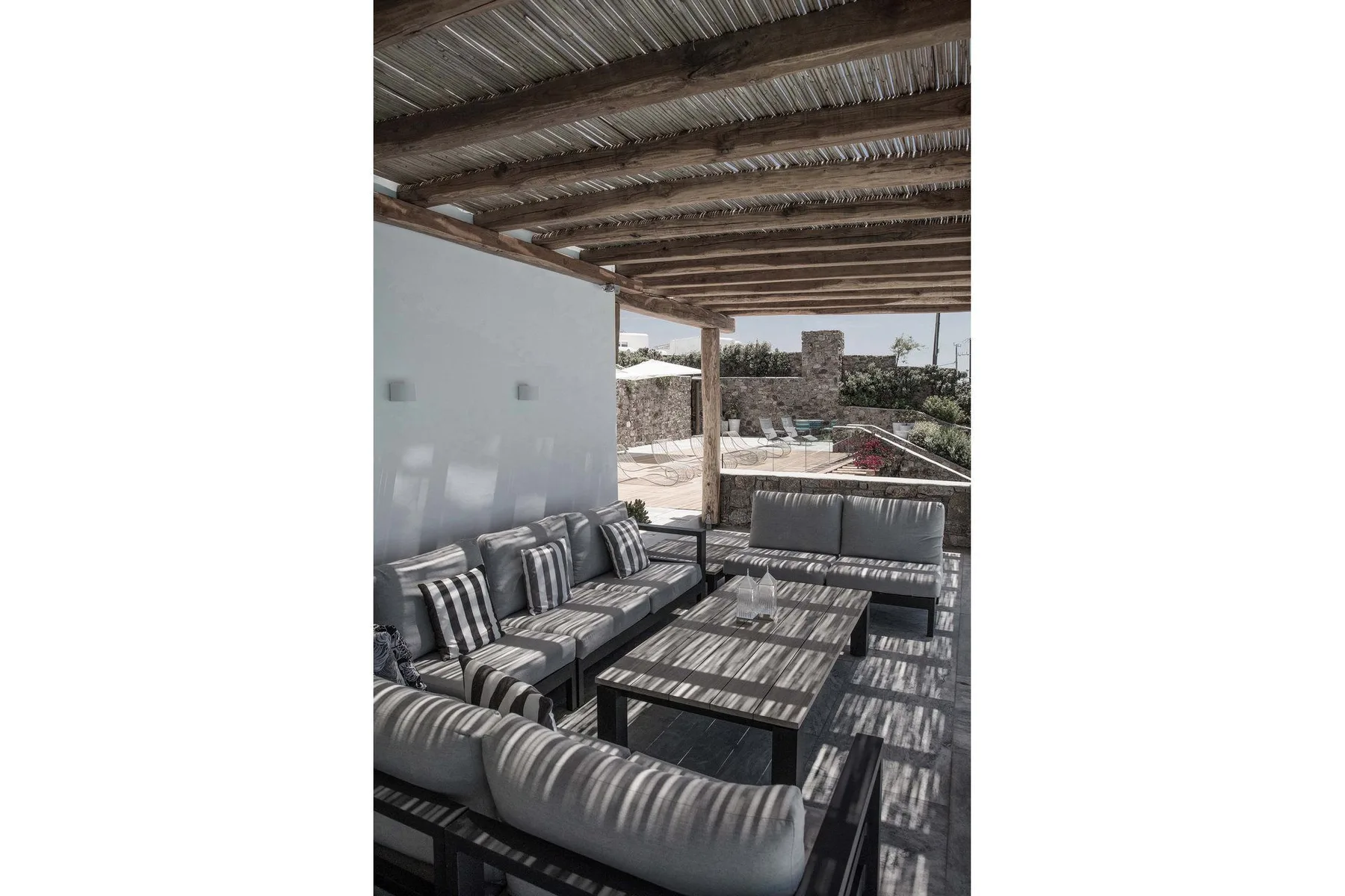 A shaded outdoor seating area with cushioned benches and a low table.