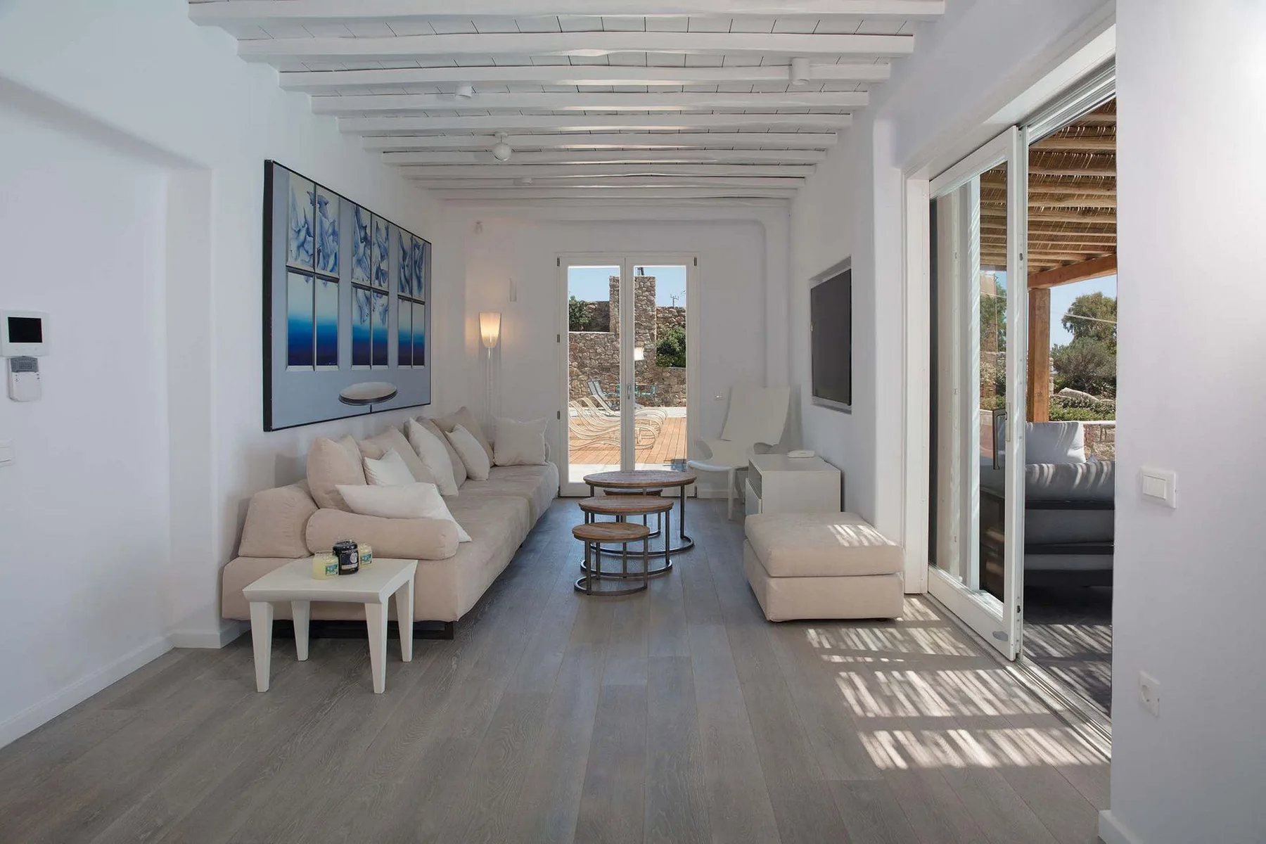 A bright living room with seating, a low coffee table, and large glass doors.
