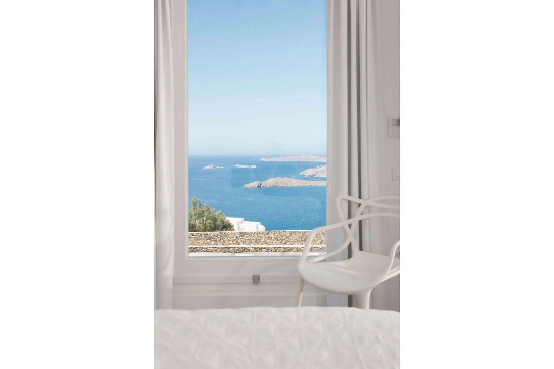A bright room with a large window overlooking the blue sea.