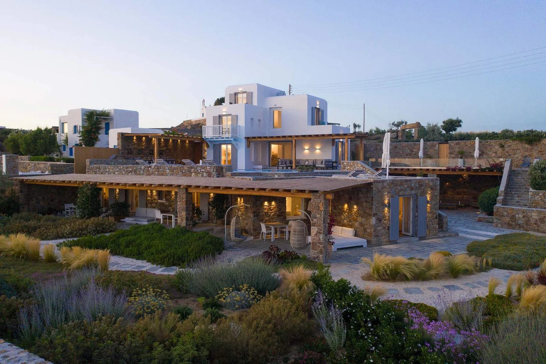A modern house with a broad covered patio opens onto landscaped gardens.