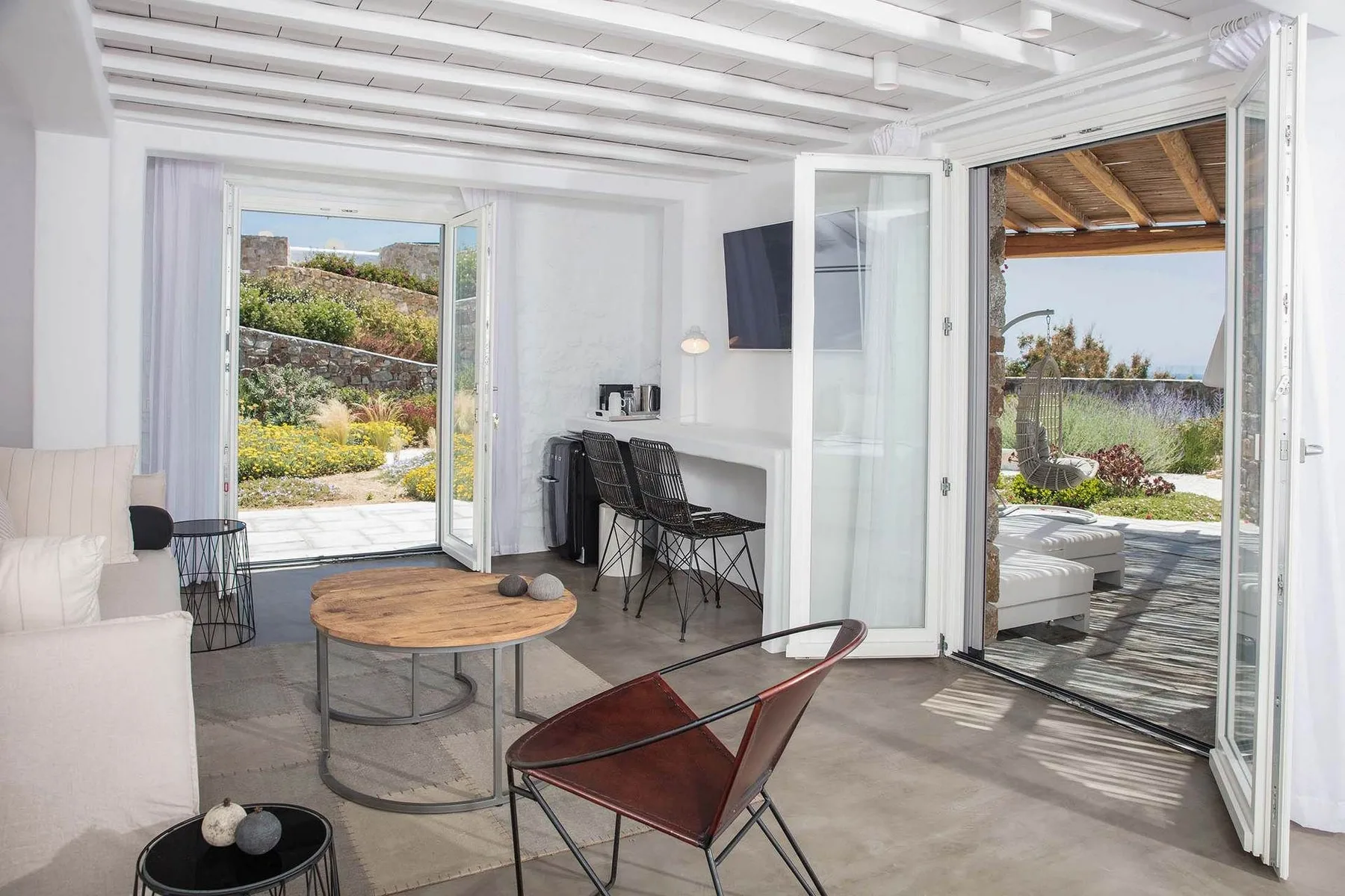 A bright living area opens through glass doors onto a garden patio.