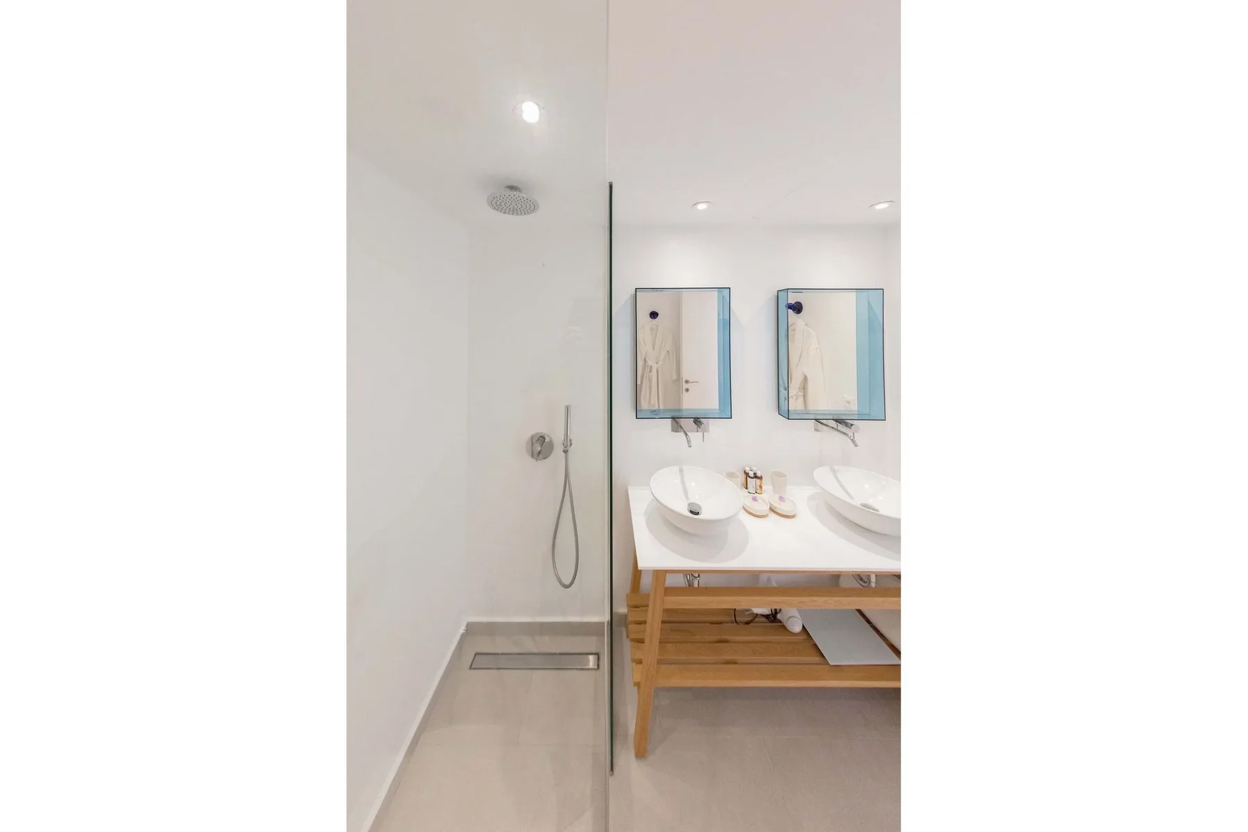 A bright bathroom has a glass shower beside a double sink vanity.